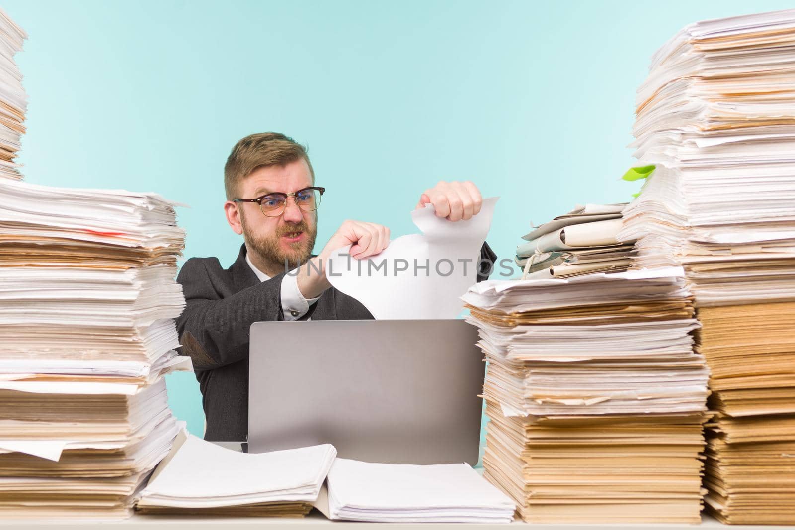 Business executive working in the office and piles of paperwork, he is overloaded with work. Breaks a paper contract and quits his job - image