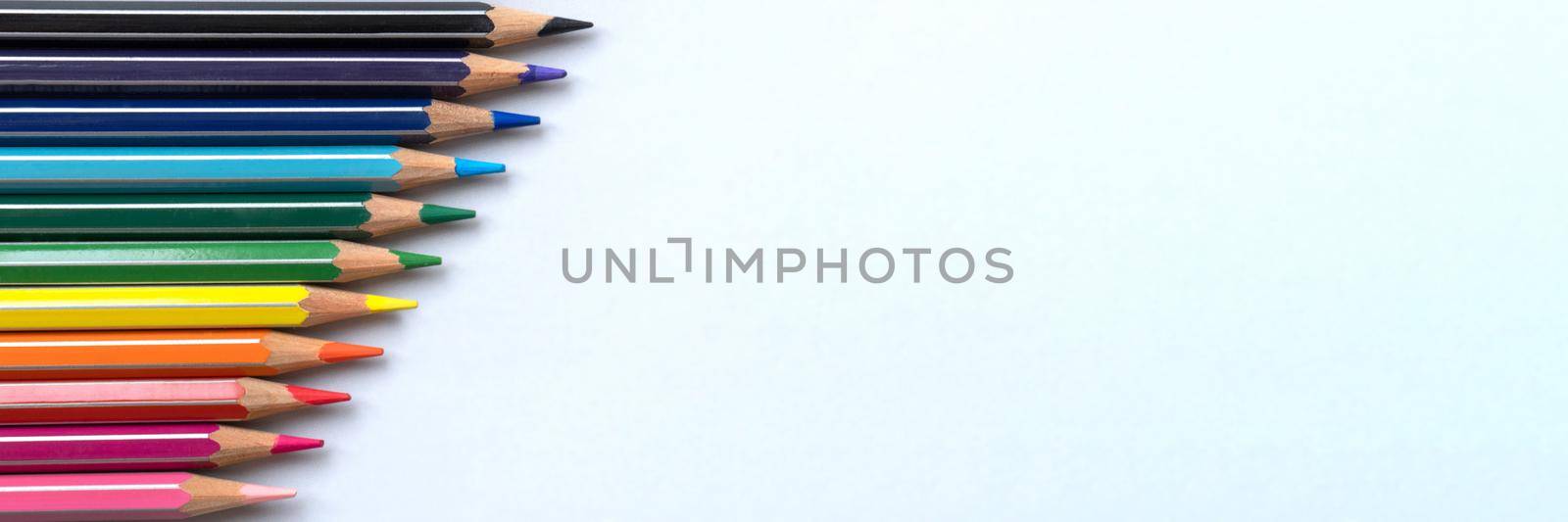 Banner of color pencils on a light gray blue background. Top view with space for text by lavsketch