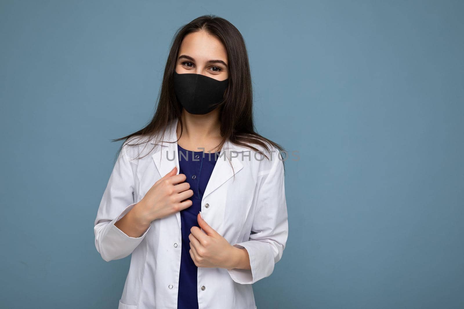 Young woman wearing an anti virus protection mask to prevent others from corona COVID-19 and SARS cov 2 infection isolated over blue background.