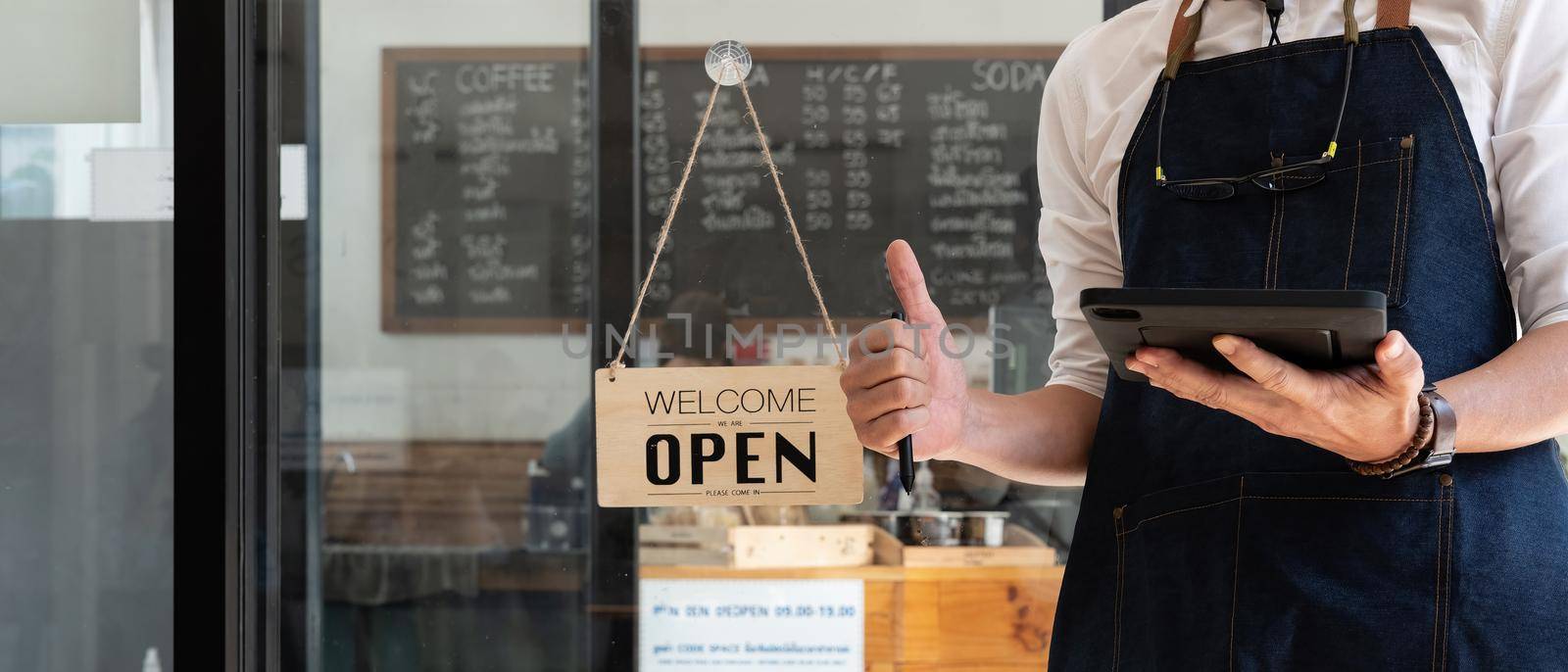 Close up of Store owner turning open sign broad through the door glass and ready to serve. hotel service, cafe-restaurant, retail store, small business owner concept. by nateemee