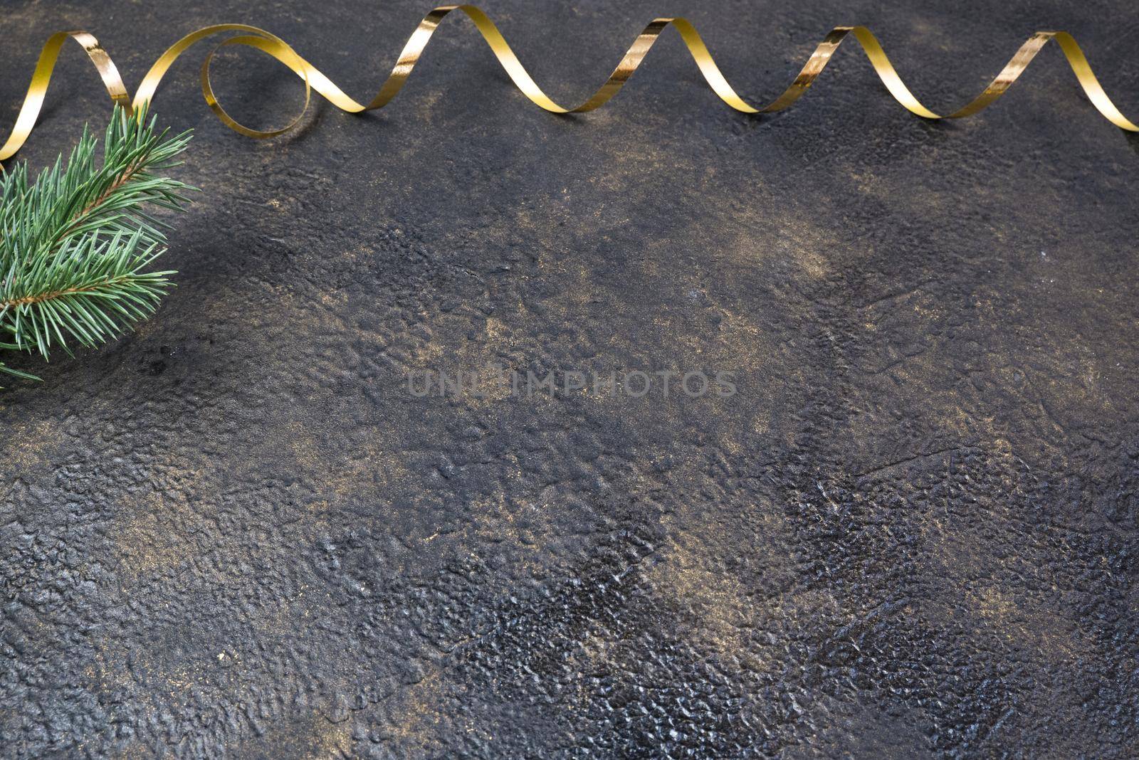 Christmas composition of fir branches and a gold ribbon in the form of a frame with a place for text on a black oil with gold embossing background.