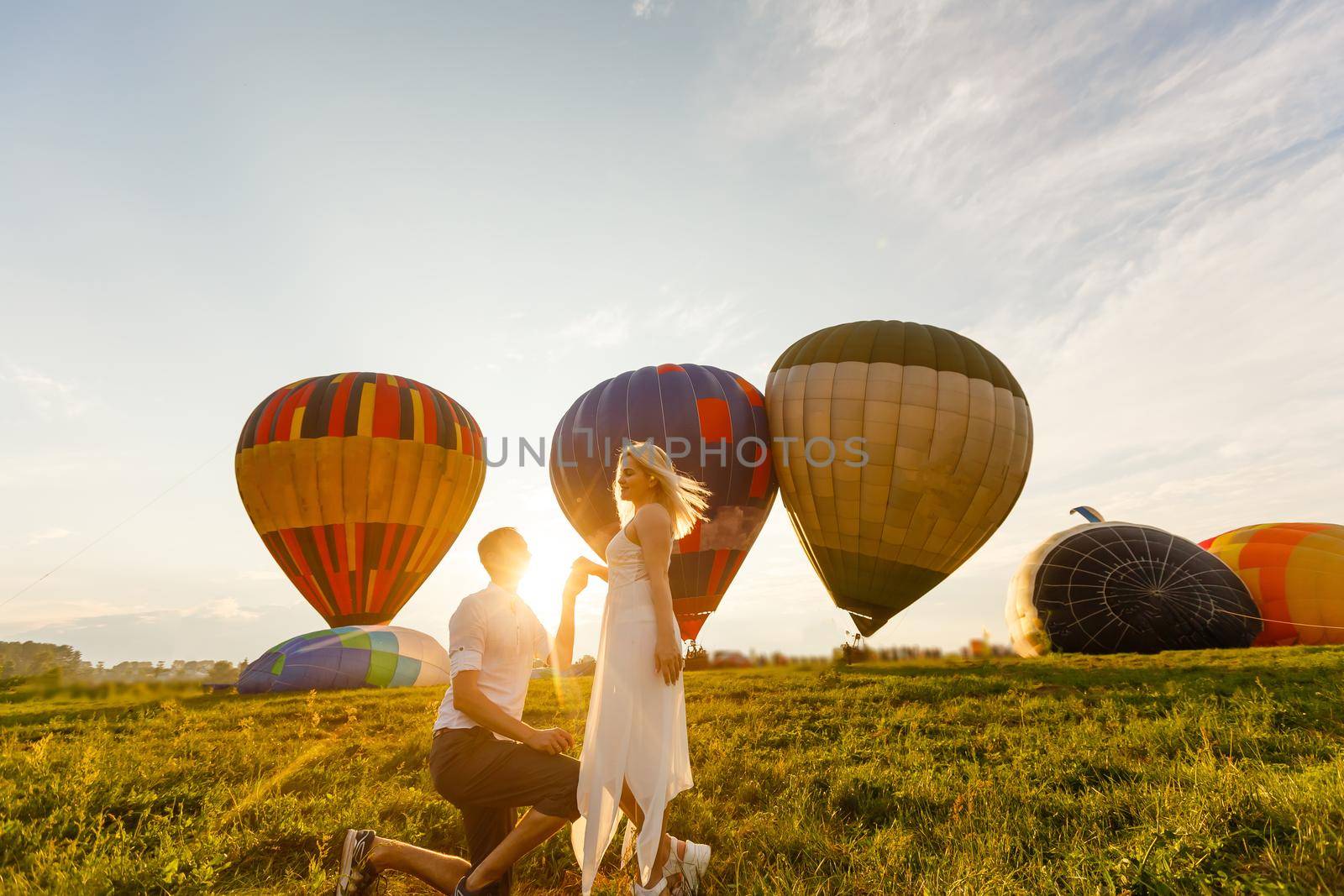 Beautiful romantic couple hugging at meadow. hot air balloon on a background