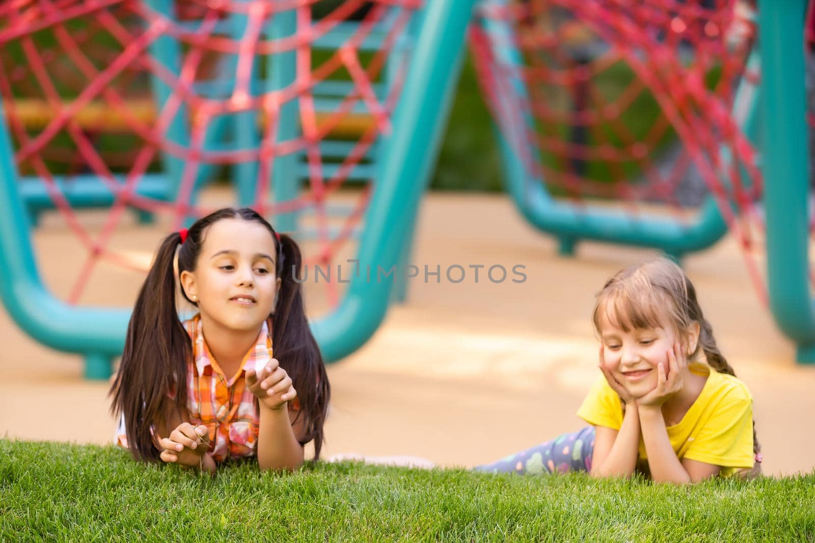 Young girls poking head through climbing rope activity using it as frame. by Andelov13