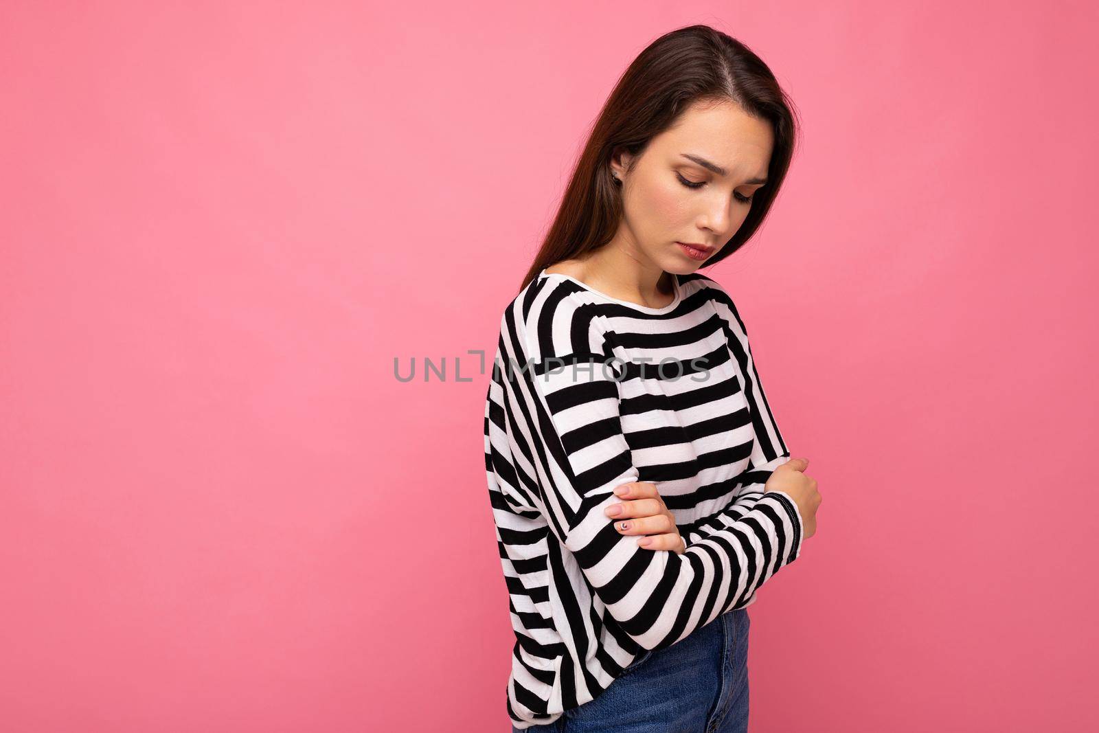Cute attractive pretty young sad upset brunette woman wearing casual striped longsleeve isolated over colorful background with copy space.