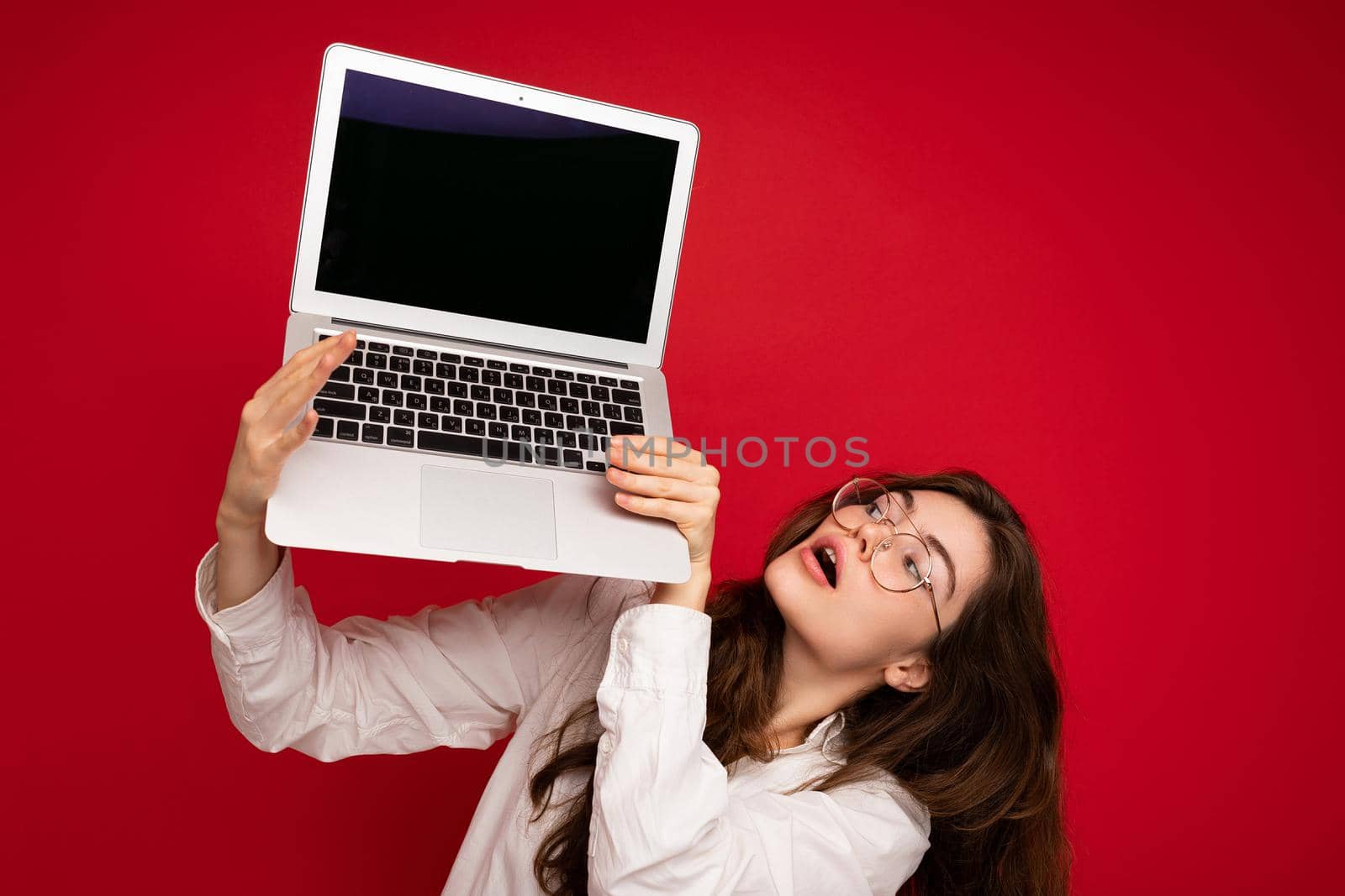 Close-up portrait of Beautiful smiling happy young woman holding computer laptop looking at netbook having fun wearing casual smart clothes isolated over wall background. Copy empty space