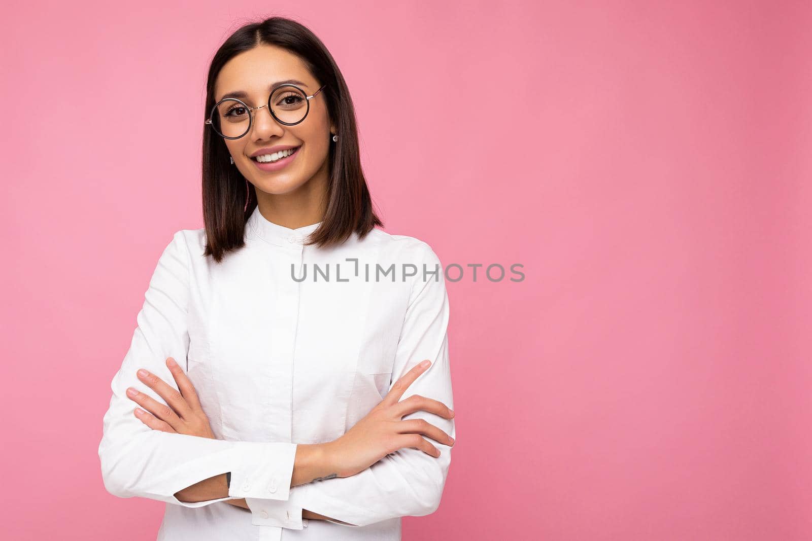Photo shot of beautiful smiling young brunette woman wearing casual clothes and stylish optical glasses isolated over colorful background looking at camera. copy space