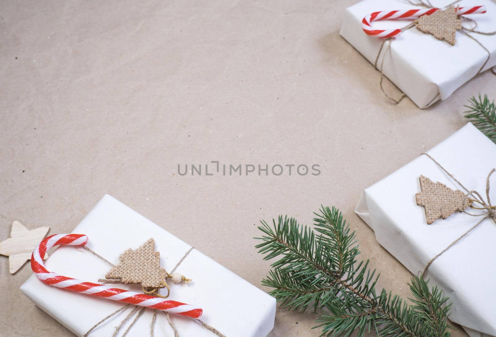 New Year's composition. Light beige parchment paper background with place for text, gift boxes, red-white sweet cane, spruce branches. Flat lay, top view. Nordic, hygge, cozy christmas concept.