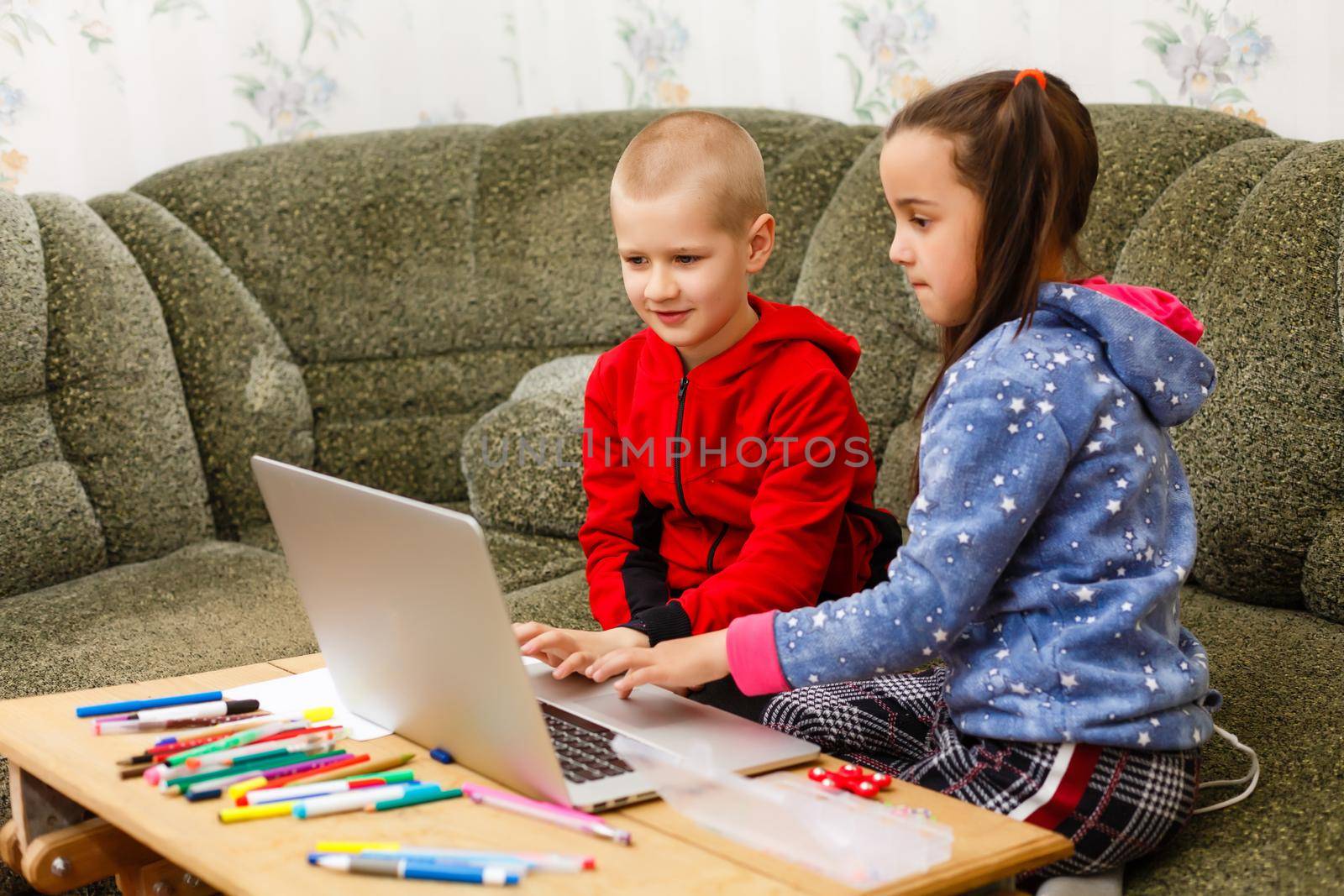 Distance learning online education. school boy and girl studying at home with laptop notebook and doing homework. Sitting at a table by Andelov13