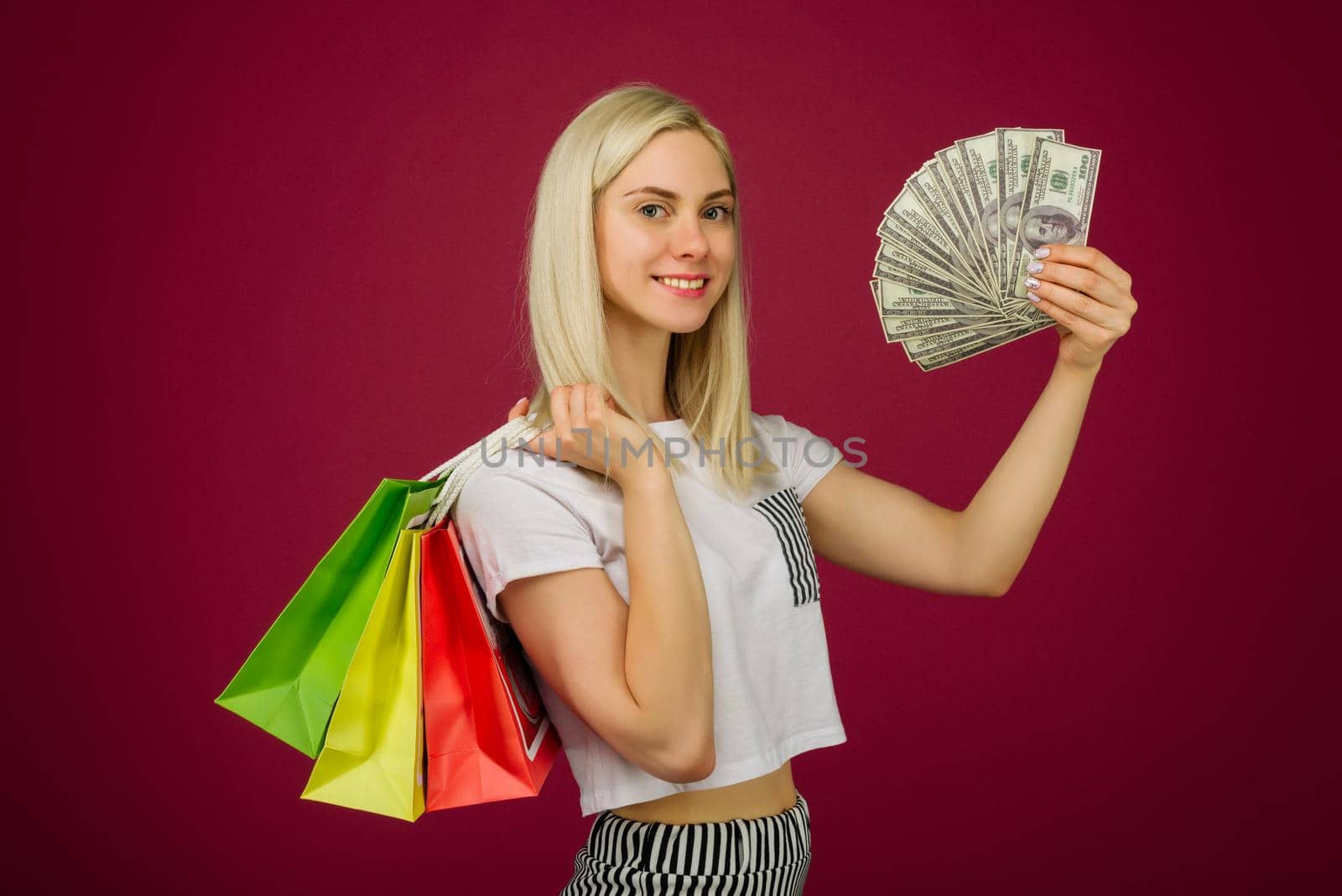 Happy girl holds one hundred dollars bills and shopping bags by zartarn