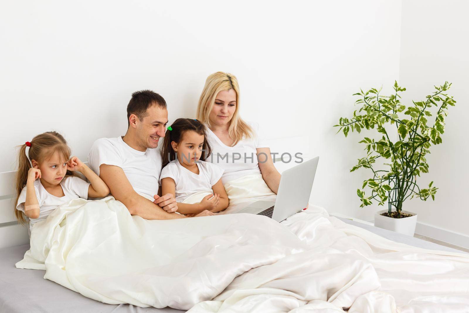 Young family resting together in parent's bed.