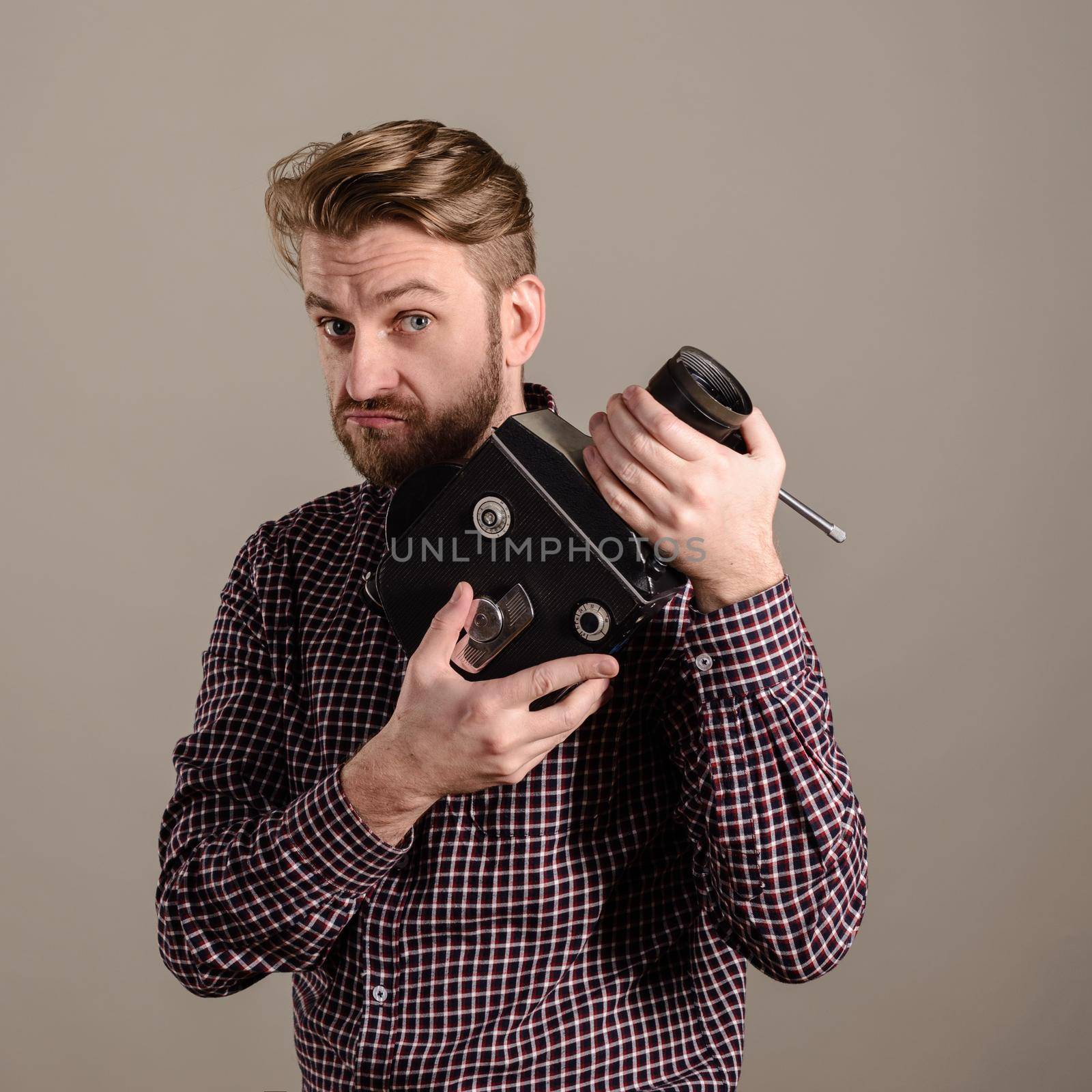 beard man in a checkered shirt holds in the hands of an old movie camera.