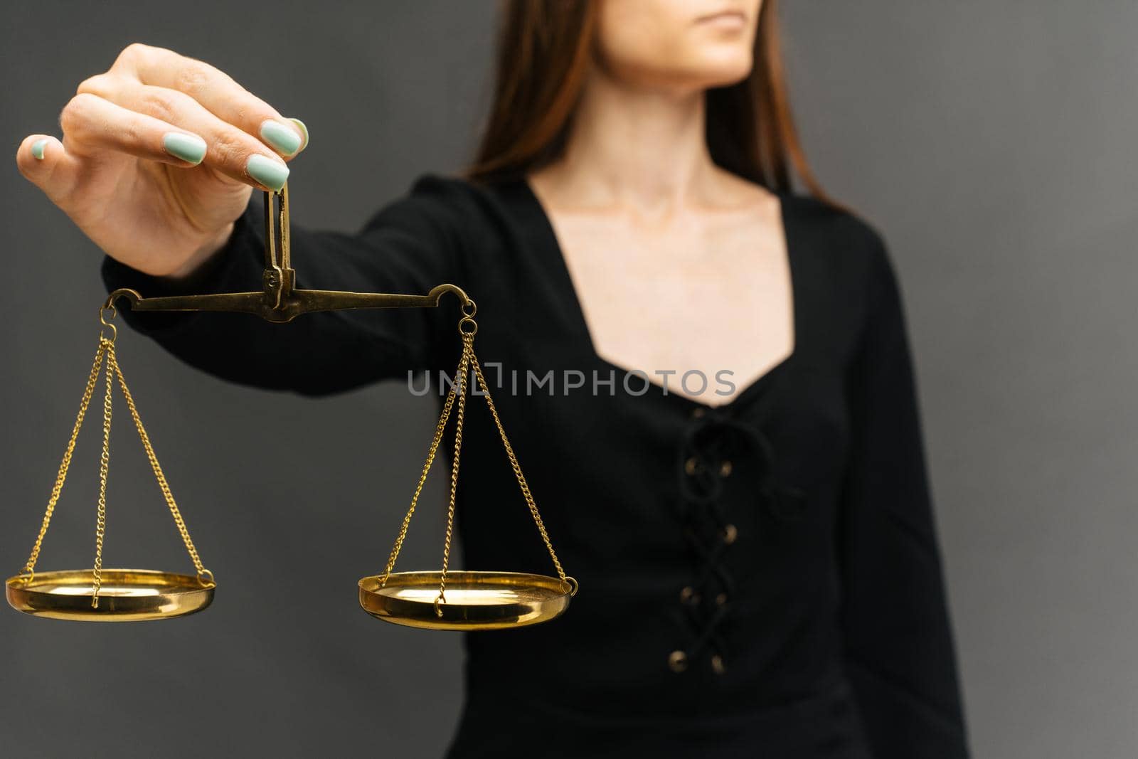 Serious woman holding the justice scale on dark background - image