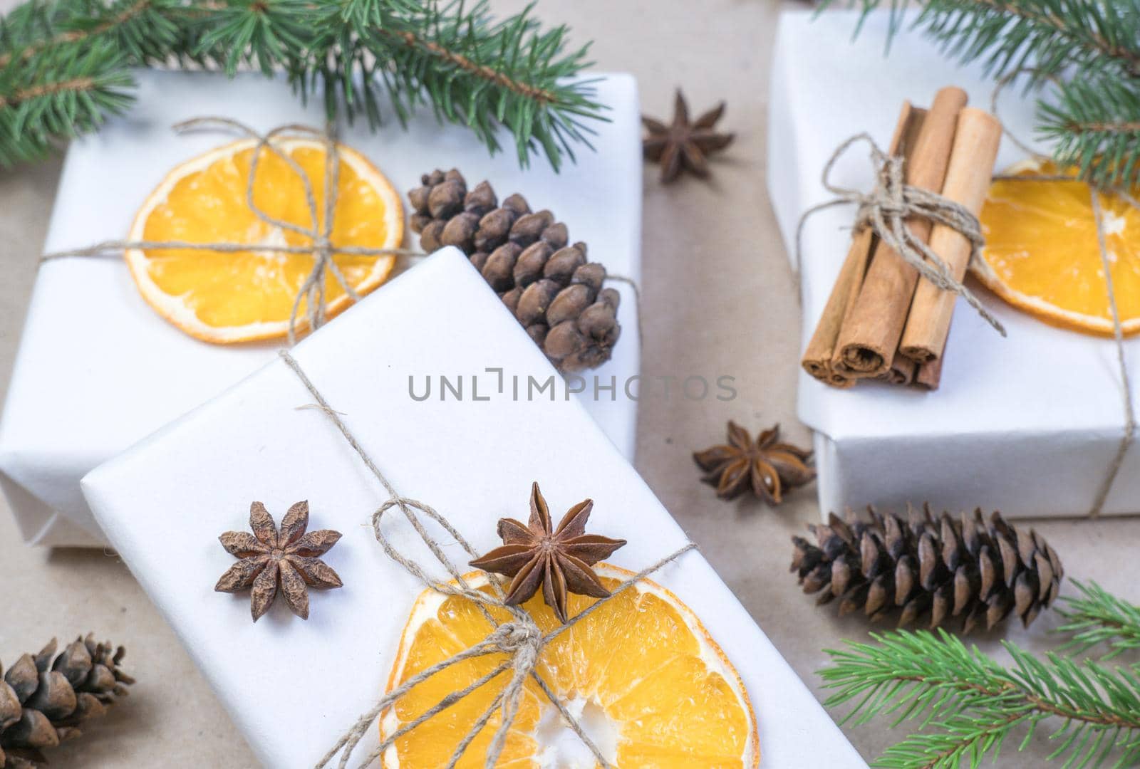 New Year's composition. On beige craft paper, gift boxes, dry orange slices, pine cones, cinnamon, cloves, spruce branches. Cozy Christmas concept