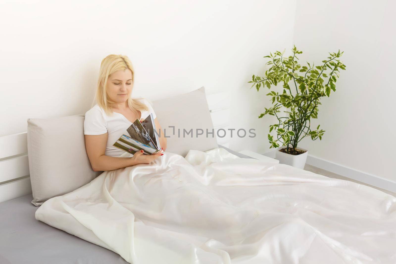 Woman holding with photo book and sitting on bed