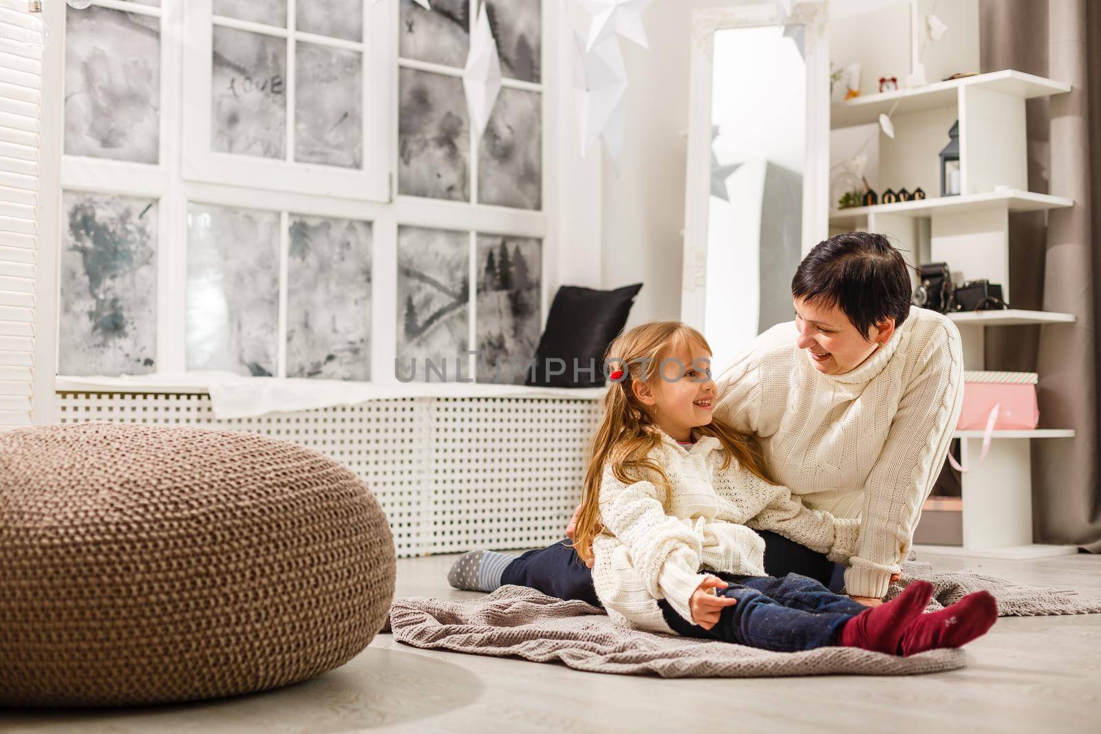 Mother and daughter unwrapping a present lying on the floor in the living room.
