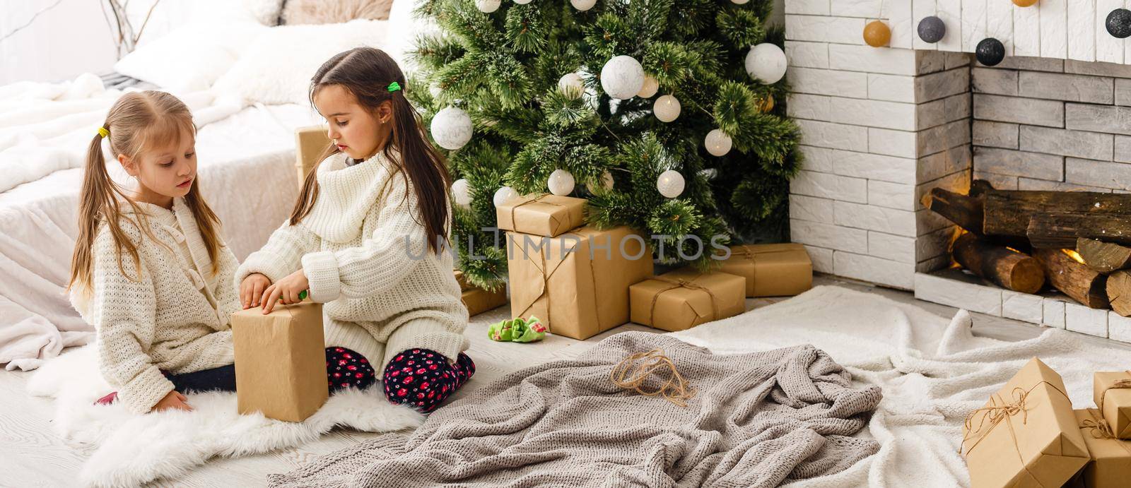 Kids little sisters hold gifts boxes interior background. What a great surprise. Small cute girls received holiday gifts. Best toys and christmas gifts. Children friends excited unpacking their gifts. by Andelov13