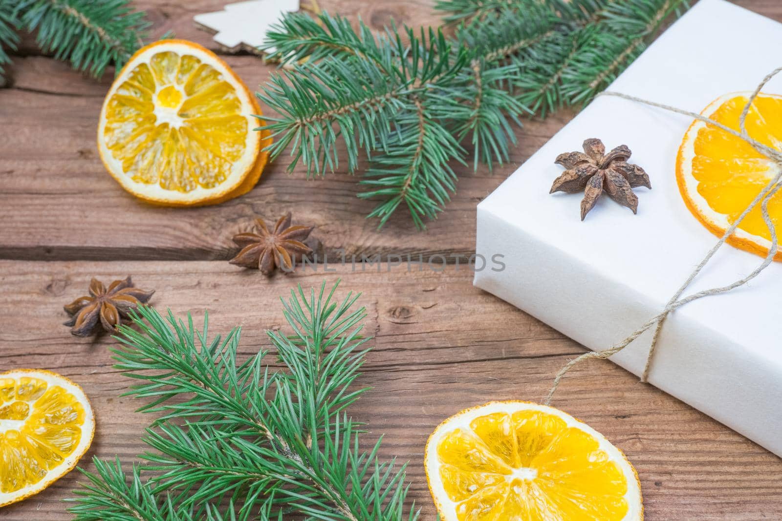 Christmas presents or gift box wrapped in kraft paper with decorations, pine cones, dry orange orange slices, cinnamon and fir branches on a rustic wooden background. Holiday concept