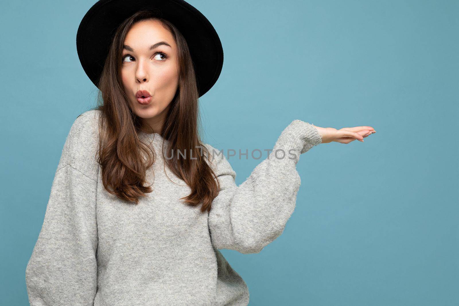 Close up photo of positive happy amazing cute nice charming young woman holding hand and showing advertisement wearing casual clothes isolated over background with copy space.