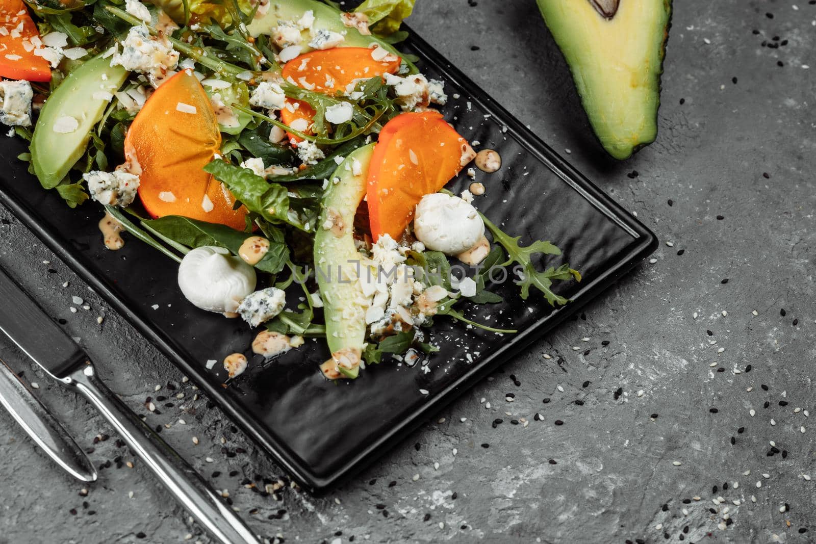 Fresh salad with fruits and greens on dark canvas background. Healthy food.