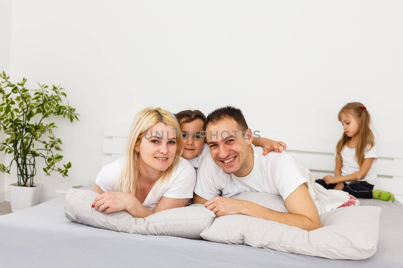 Young family resting together in parent's bed.