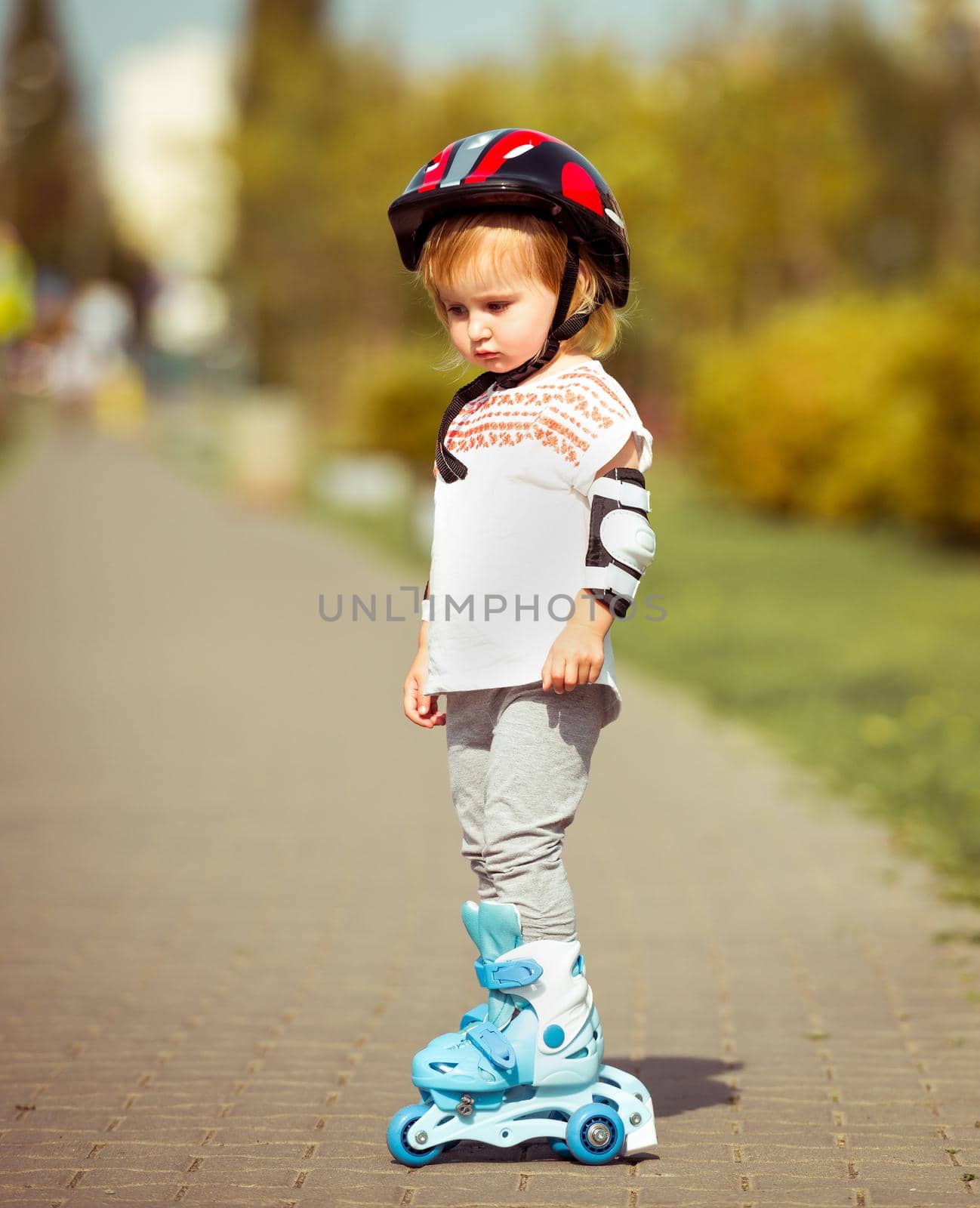 two year old girl in roller skates and a helmet by tan4ikk1