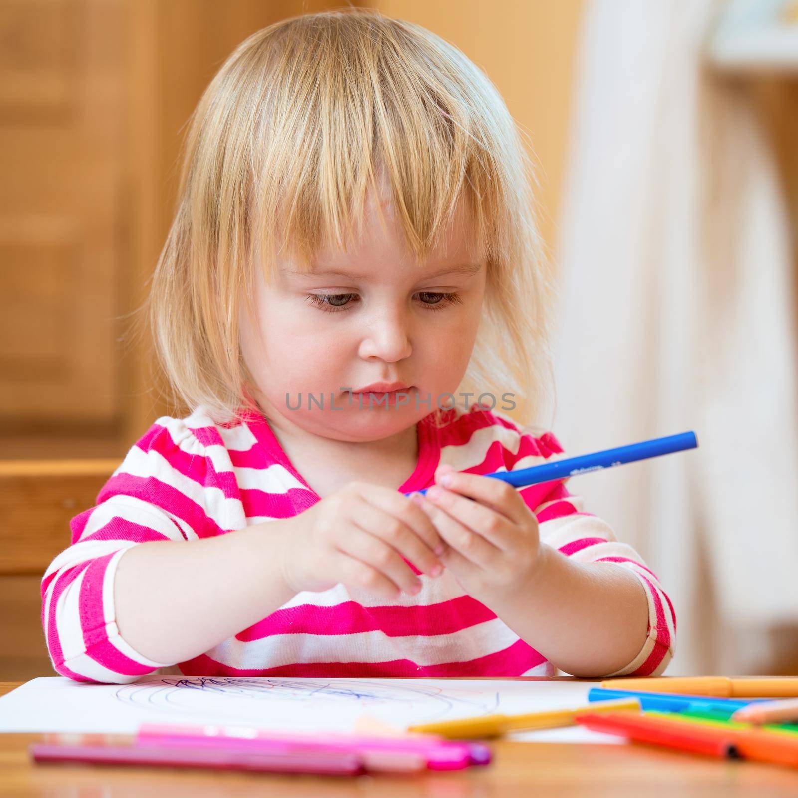 Cute three-year-old girl draws felt-tip pens at home
