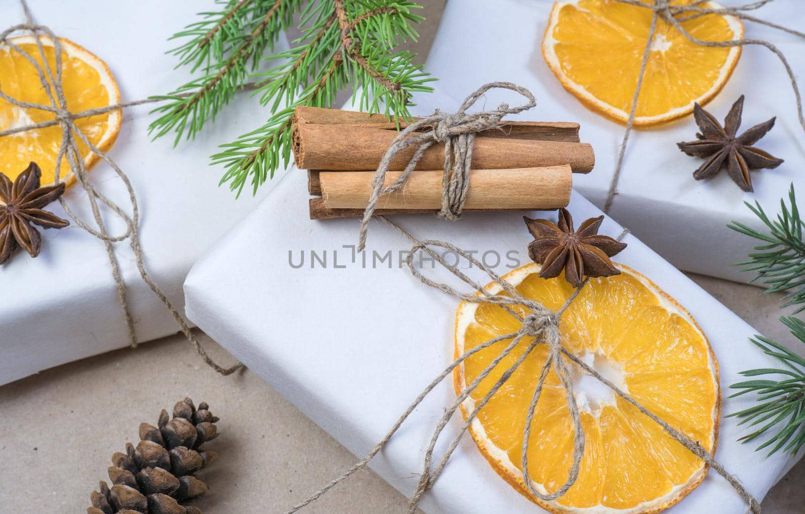 New Year's composition. On beige craft paper, gift boxes, dry orange slices, pine cones, cinnamon, cloves, spruce branches. Cozy Christmas concept. by Ekaterina34