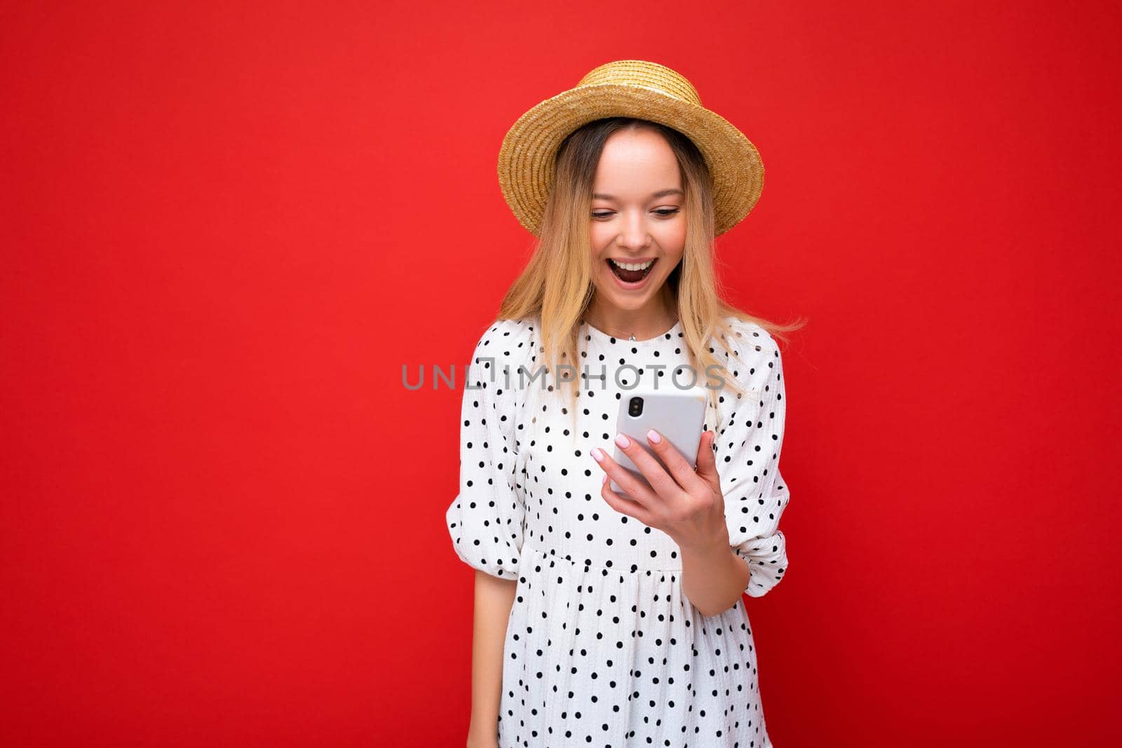 Beautiful young woman wearing casual clothes standing isolated over background surfing on the internet via phone looking at mobile screen.