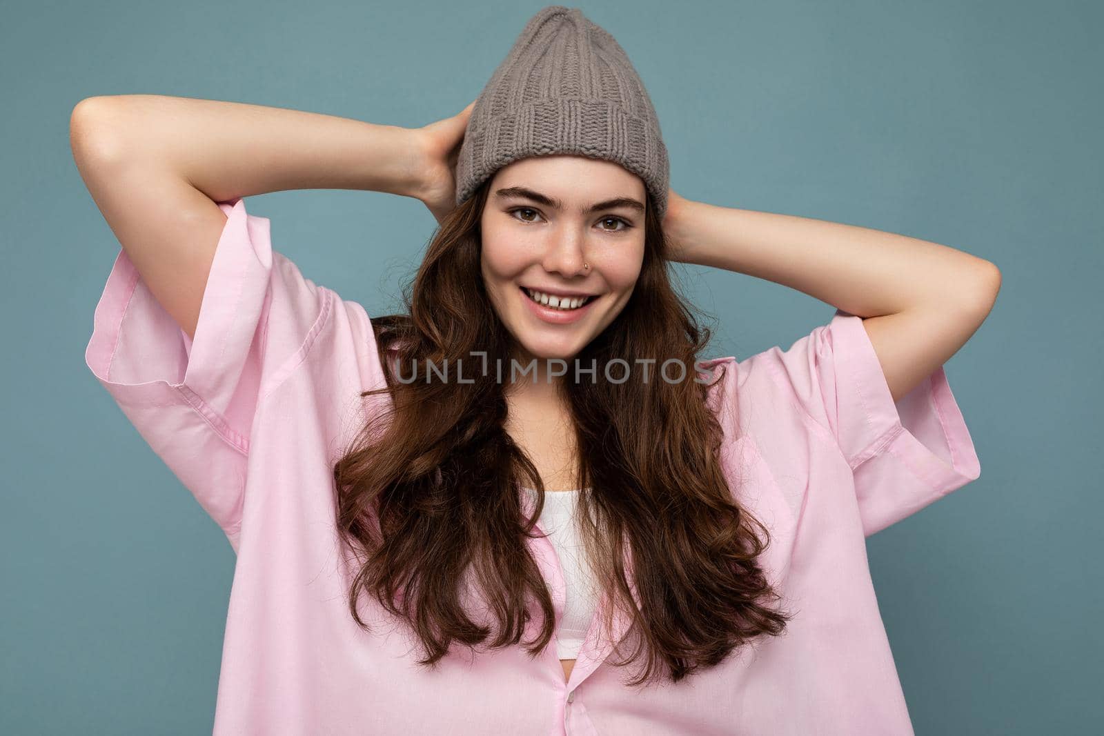 Attractive smiling happy young brunette woman standing isolated over colorful background wall wearing everyday stylish outfit showing facial emotions looking at camera by TRMK