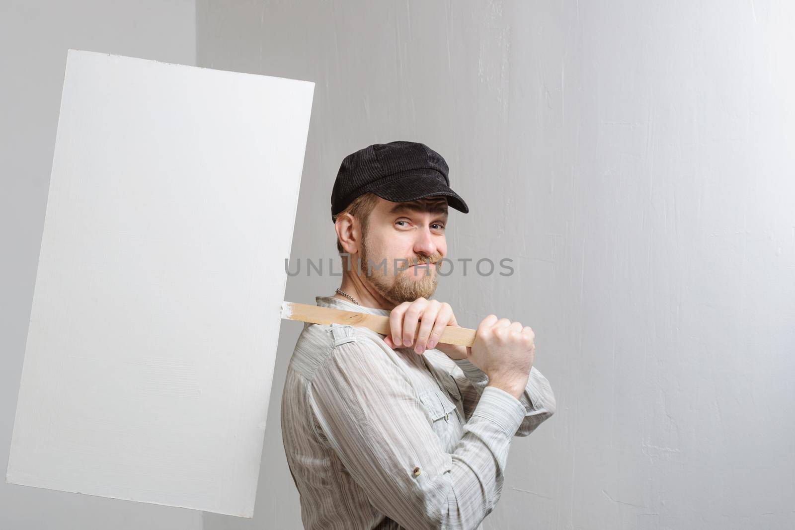 Working in a cap holding a banner over his head at white wall