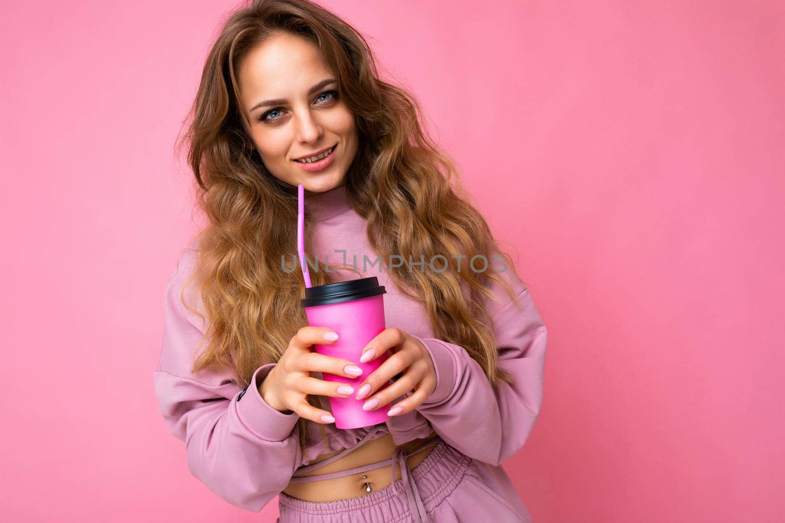 Beautiful young positive brunette woman wearing casual stylish clothes isolated over colorful background wall holding paper cup for mockup drinking coffee looking at camera.
