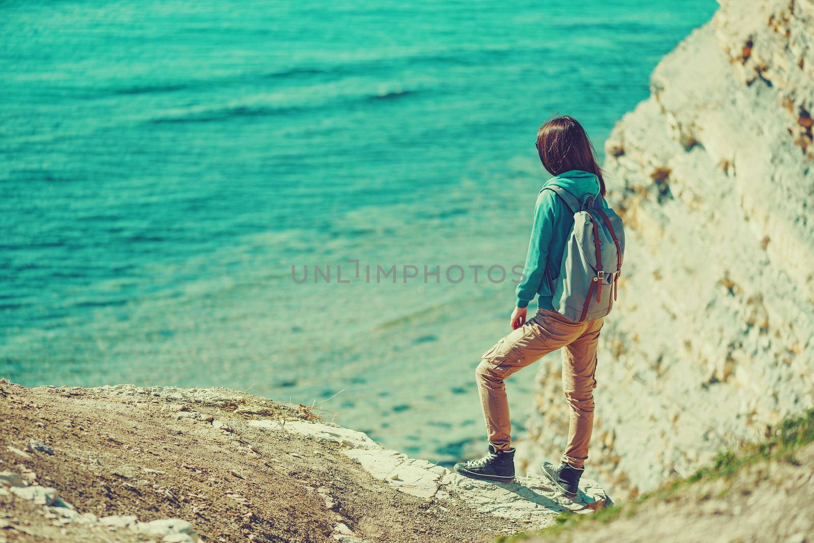Traveler girl standing on coast and enjoying view of sea in summer. Image with instagram color effect