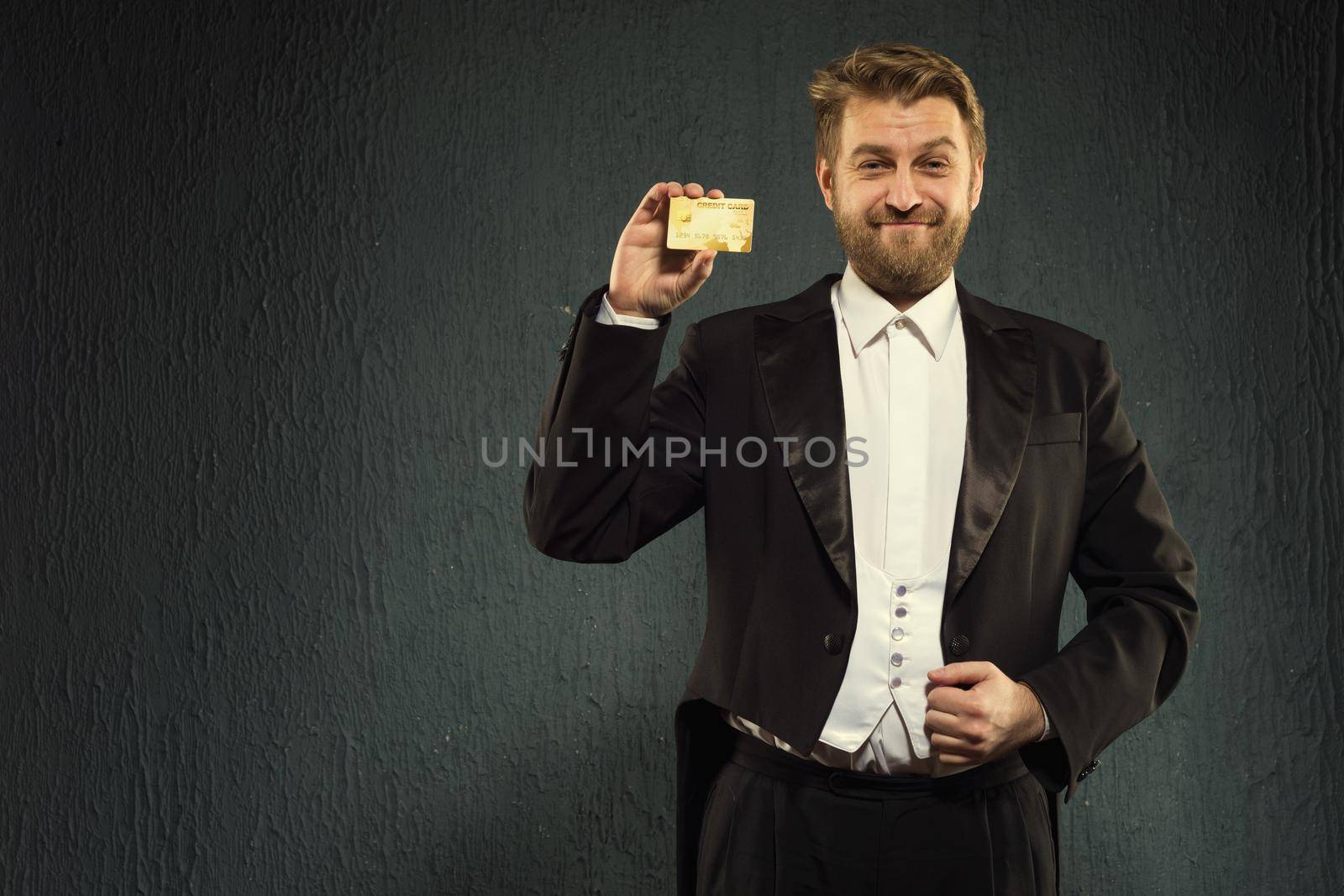 Positive man in a tailcoat offers a credit card. by zartarn