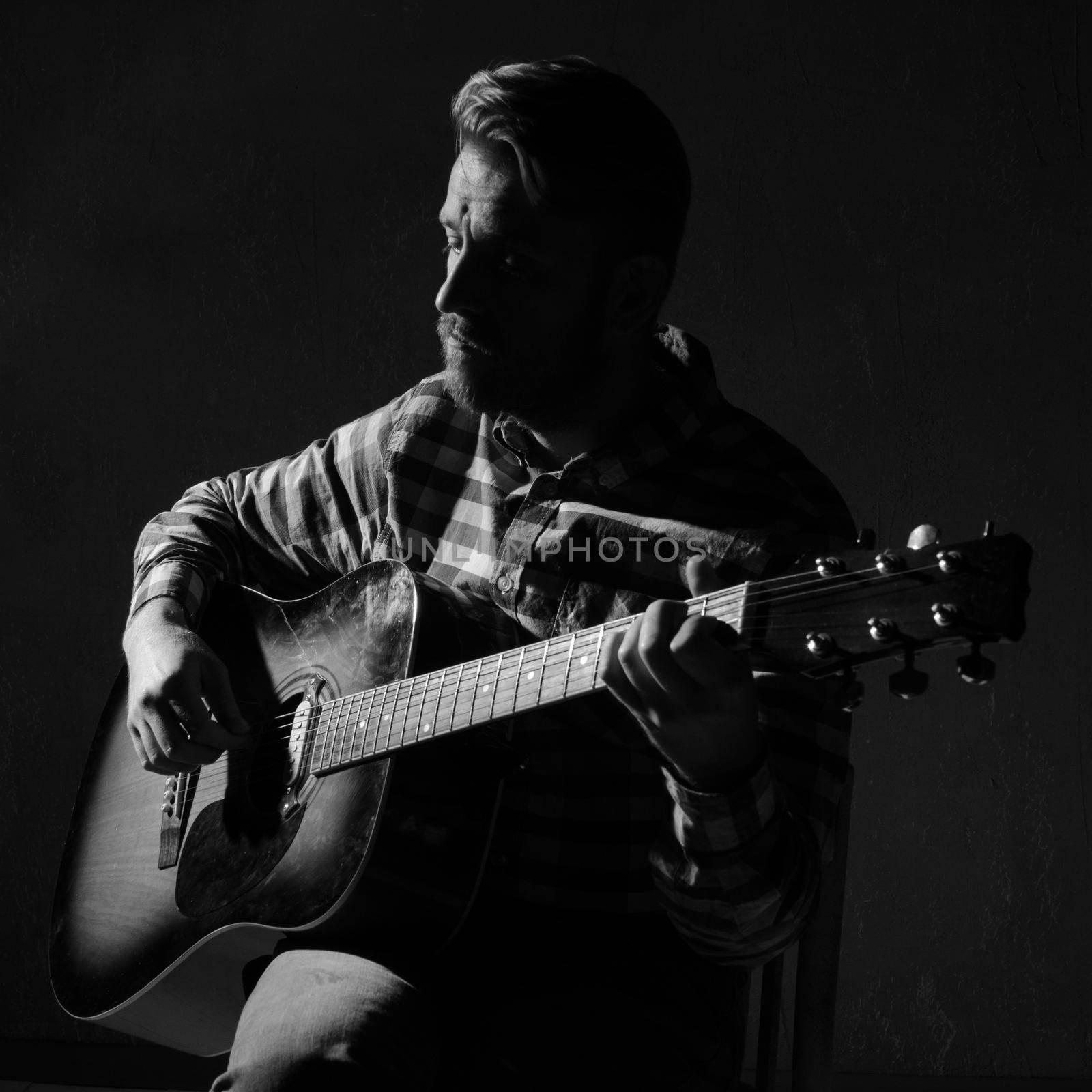 Caucasian bearded male musician playing guitar on stage, focus on hand. black and white by zartarn