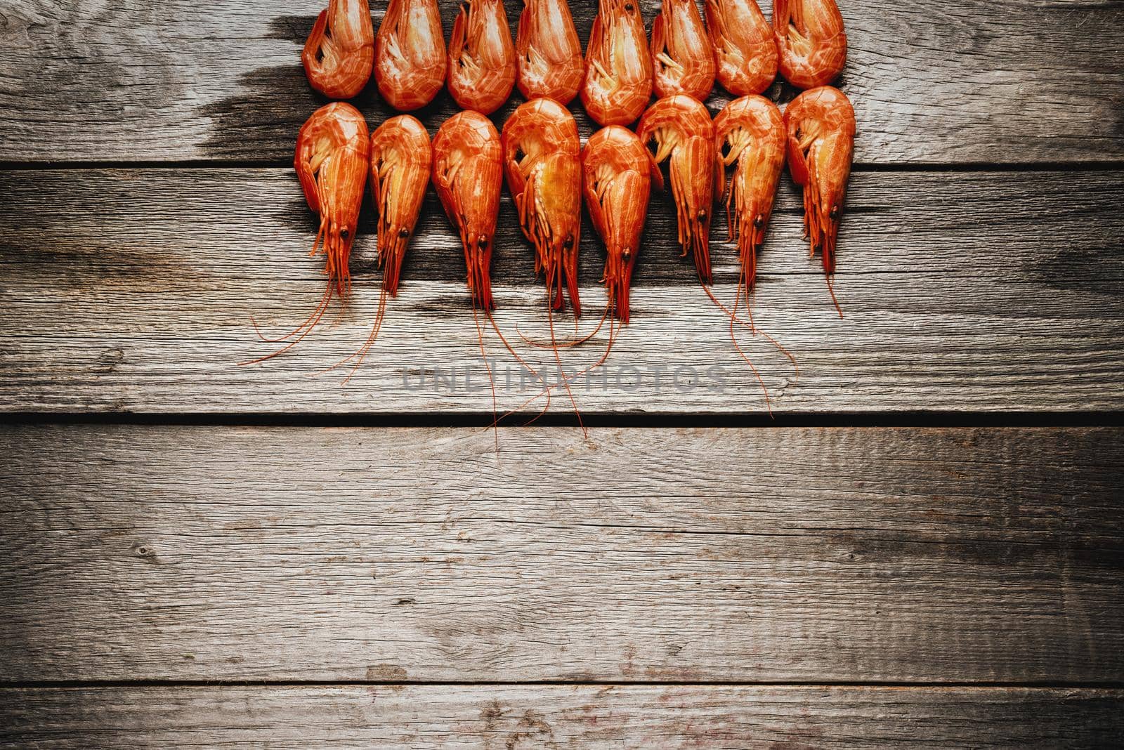 Red boiled shrimps on a wooden background, space for text