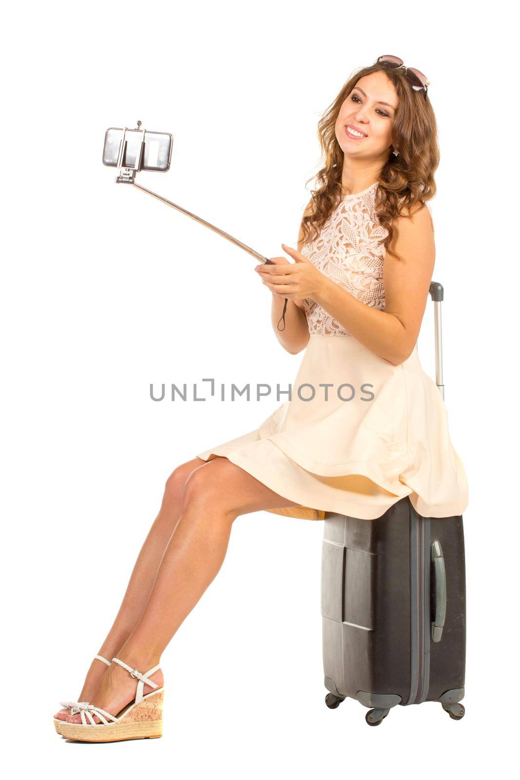 Happy woman making selfie on her smartphon on selfie stick, isolated on white.