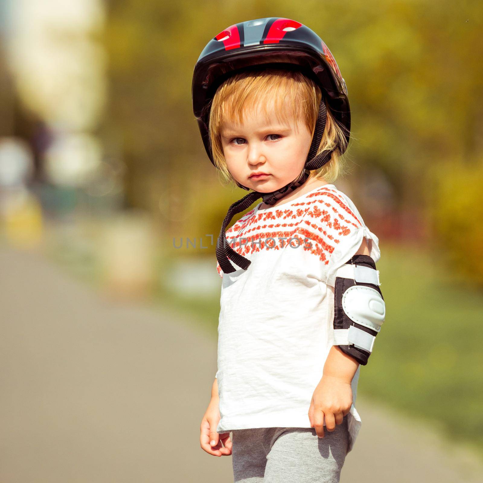 two year old pretty girl in a helmet on the street close-up