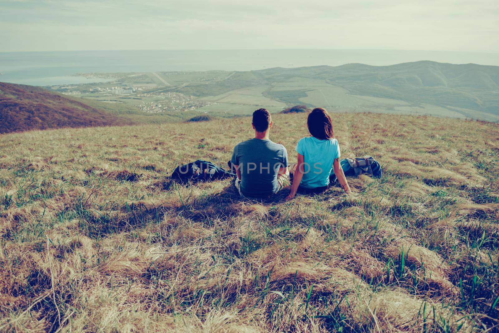 Couple in love sitting on mountain meadow and enjoying view of nature