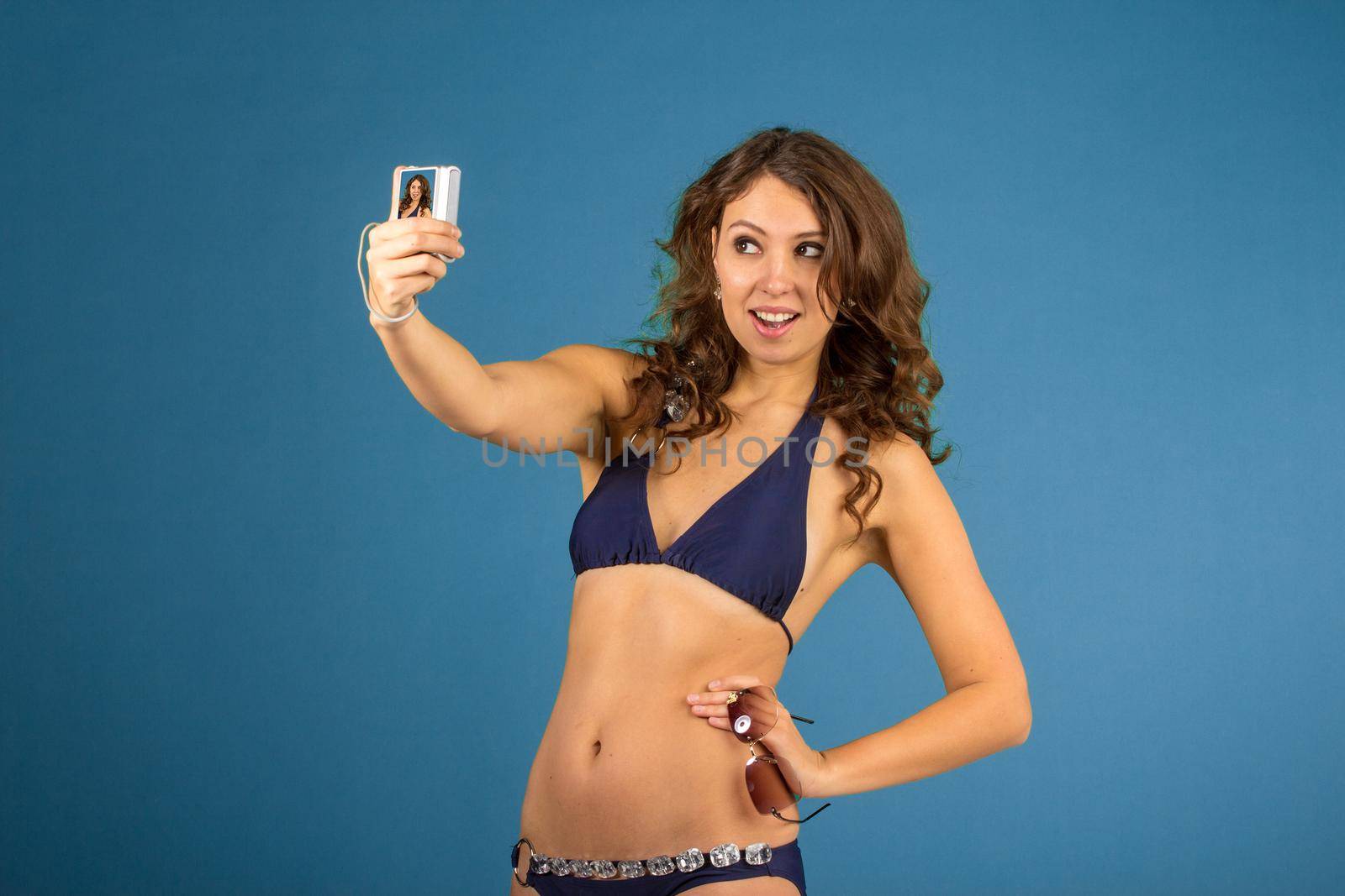 Portrait of smiling woman with camera and while standing against blue isolated background.