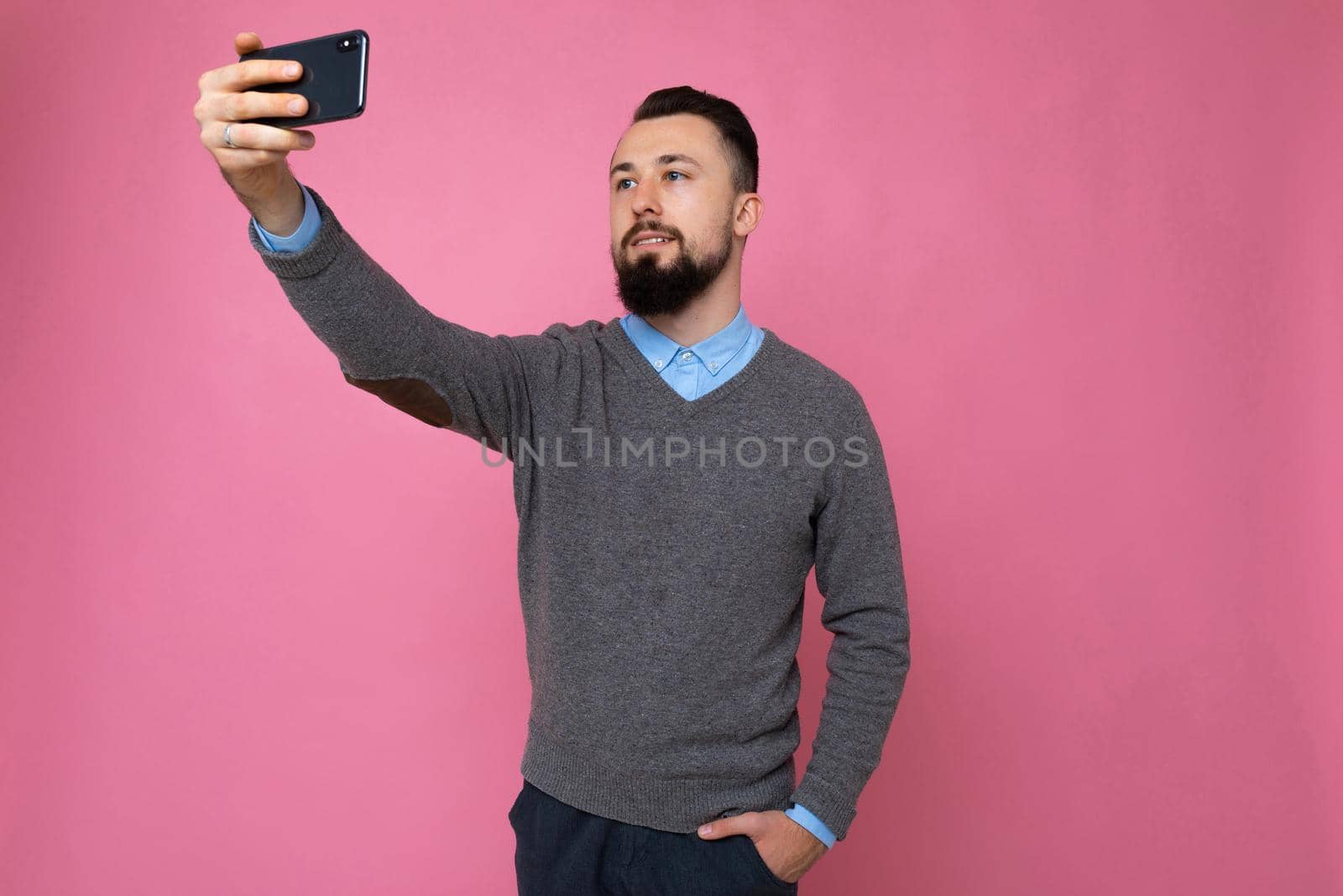 guy on a pink background takes a selfie.