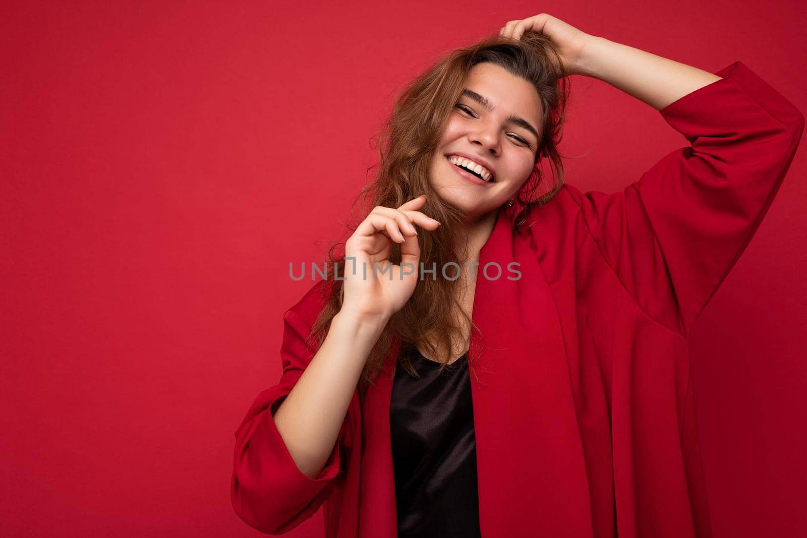 Portrait of positive cheerful fashionable woman in formalwear looking at camera isolated on red background with copy space by TRMK