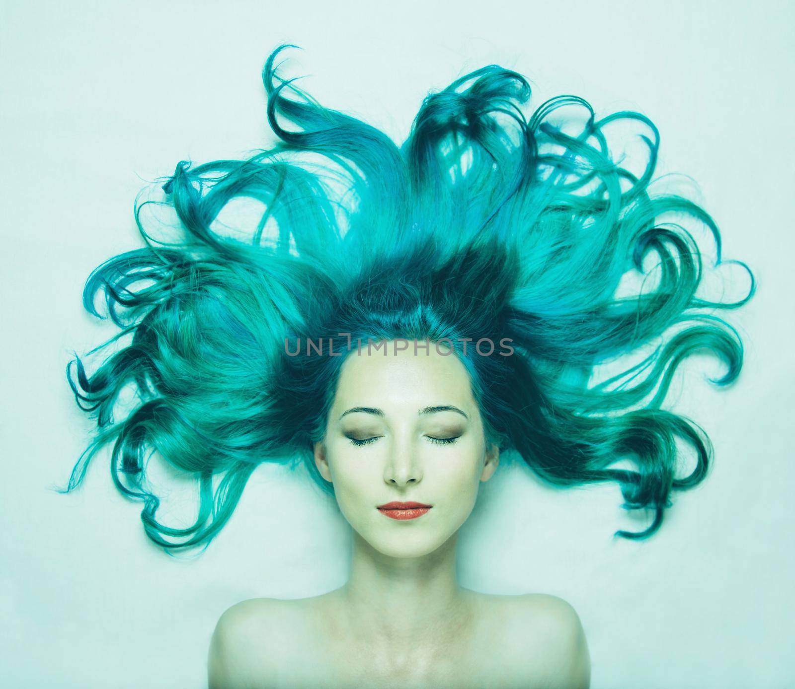 Portrait of smiling beautiful young woman with closed eyes and long hair of turquoise color, top view. Image of mermaid