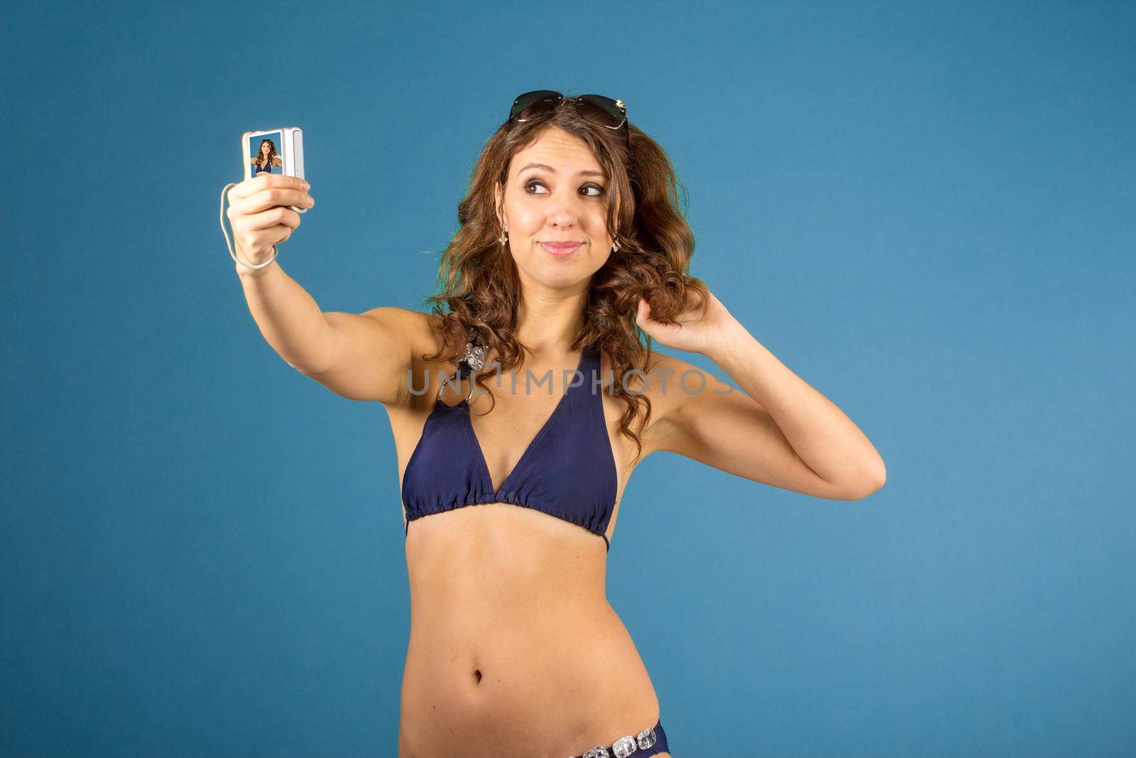 Portrait of smiling woman with camera and while standing against blue isolated background.