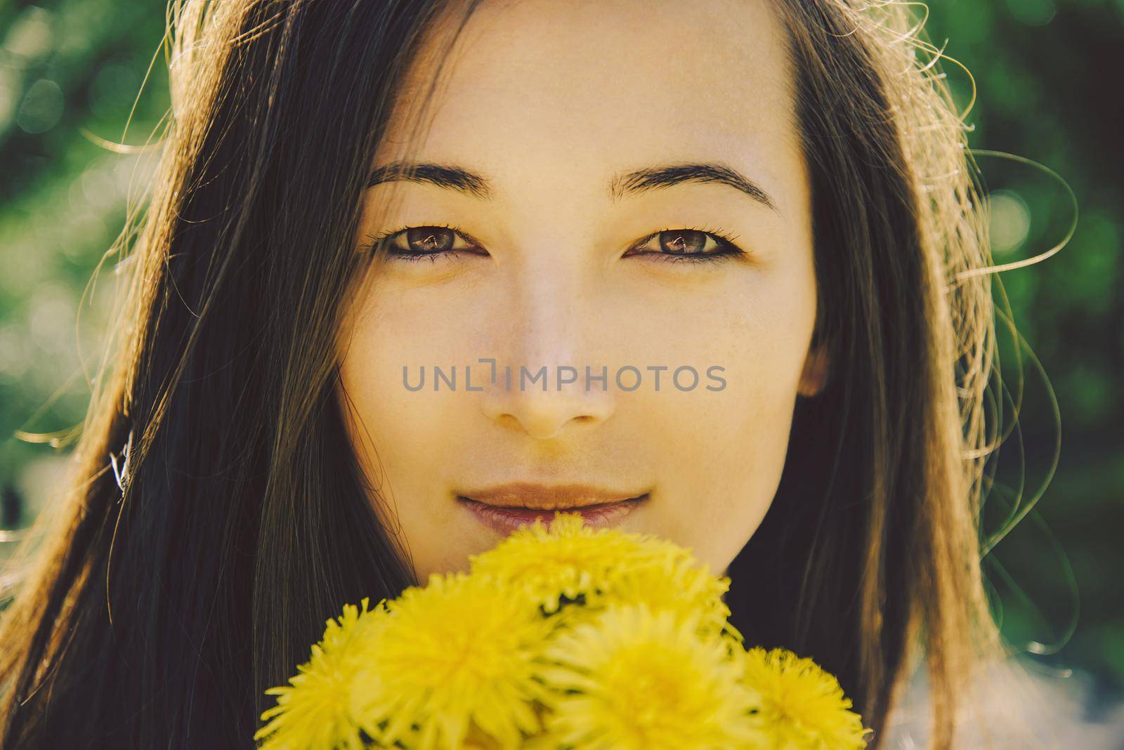 Portrait of beautiful girl with bouquet of yellow dandelions outdoor in summer, concept of summer mood
