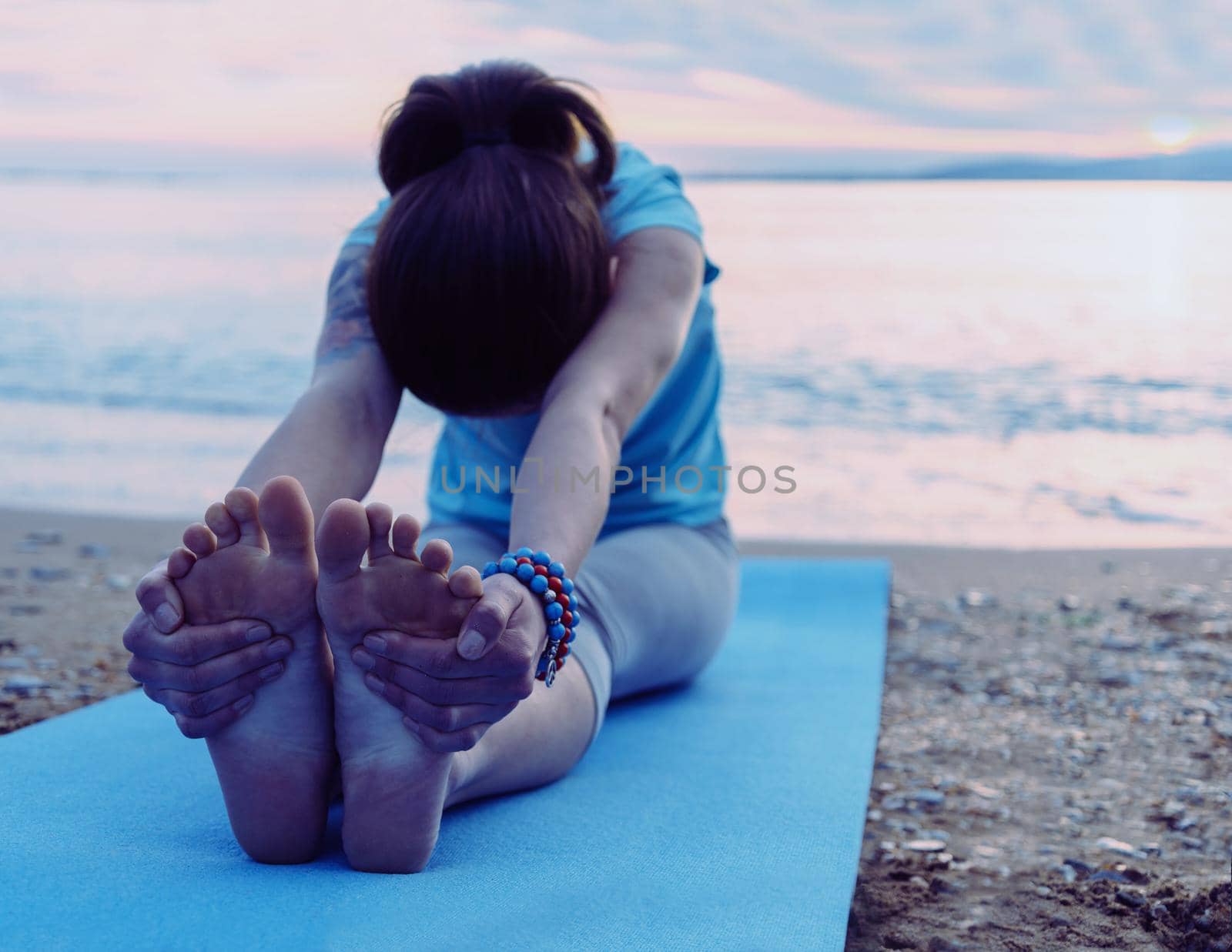 Woman doing yoga exercise on beach by alexAleksei