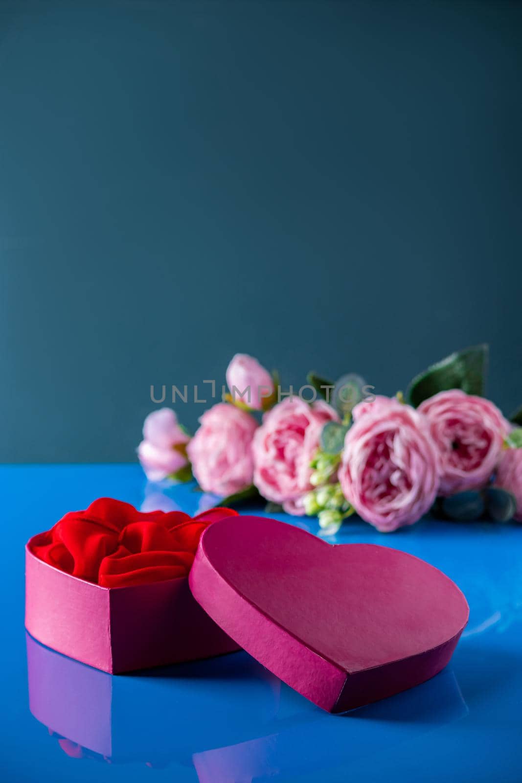 Heart shaped open gift box on blue background. by Statuska