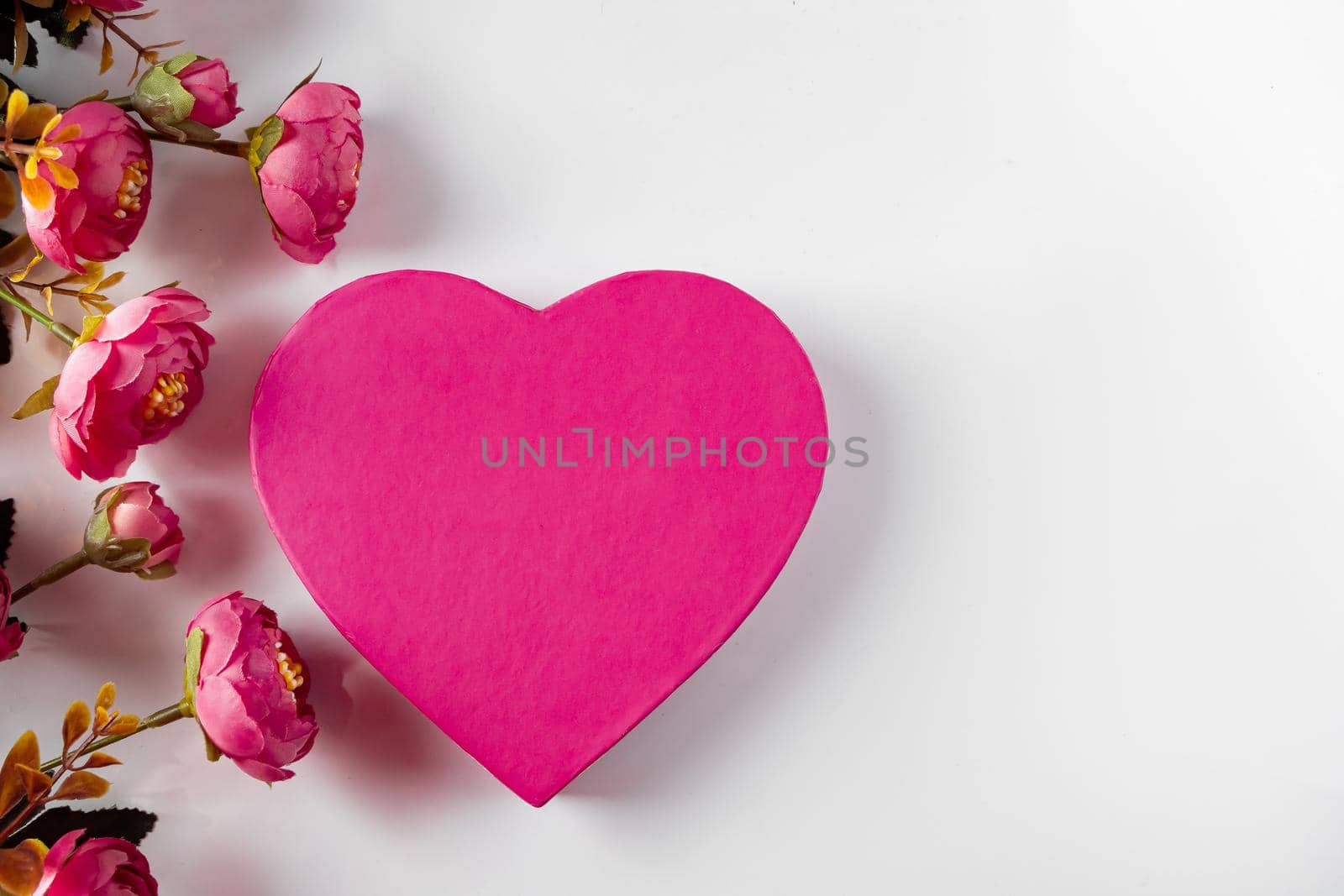 Pink heart for valentines day on a background of flowers. Frame of pink flowers and a big heart on a white background. Design for valentines day, place for text.