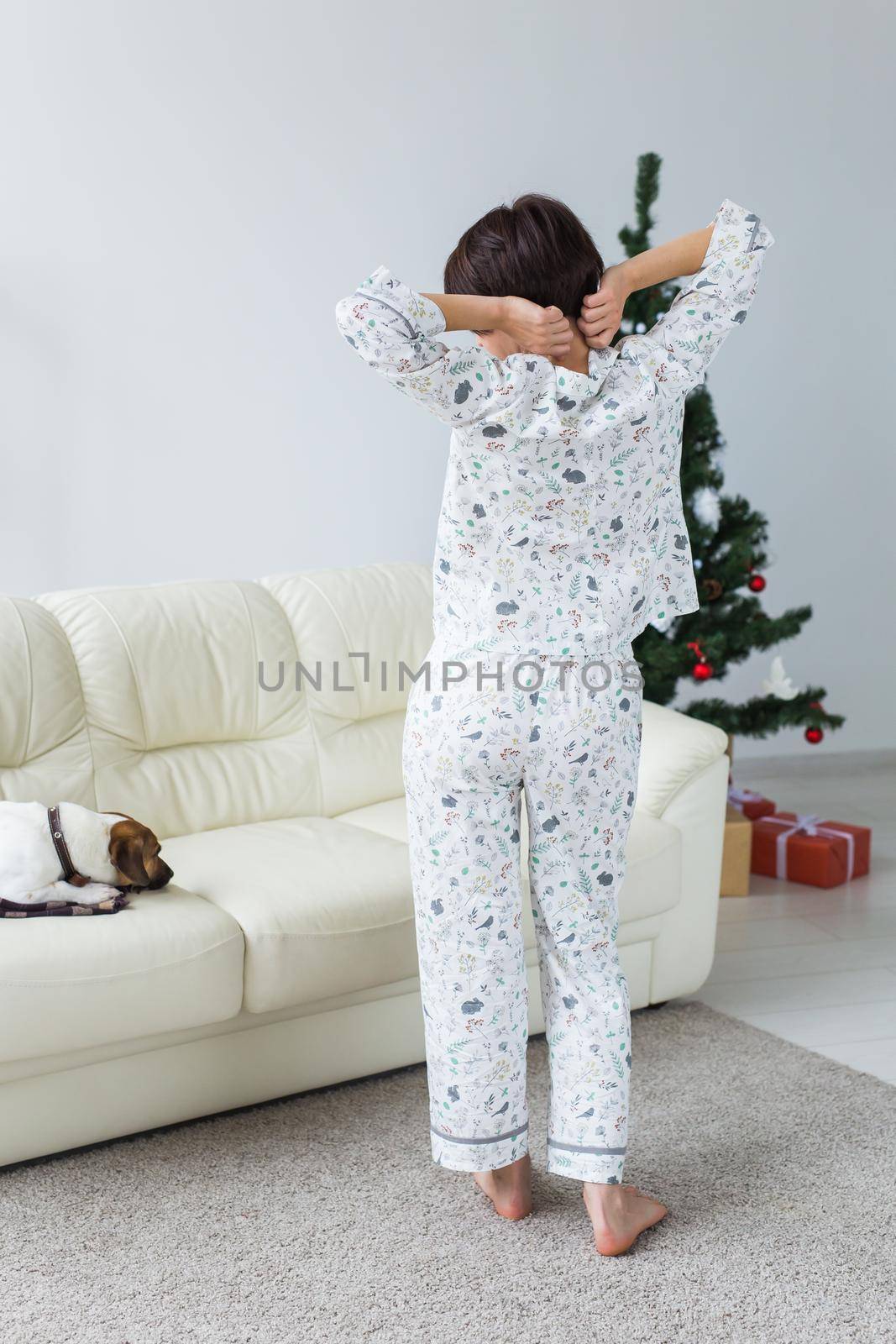 Happy young woman with lovely dog in living room with christmas tree. Holidays.
