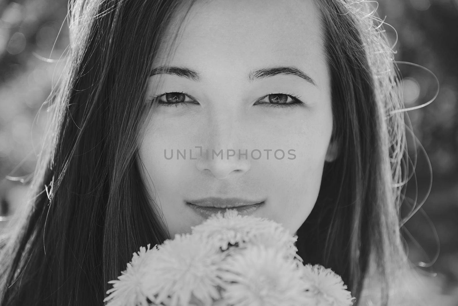 Portrait of beautiful young woman with bouquet of dandelions outdoor in summer, black and white image