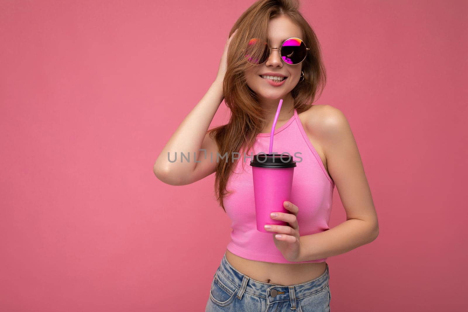 Beautiful sexy young positive woman wearing casual stylish clothes isolated over colorful background wall holding paper cup for mockup drinking coffee looking at camera by TRMK
